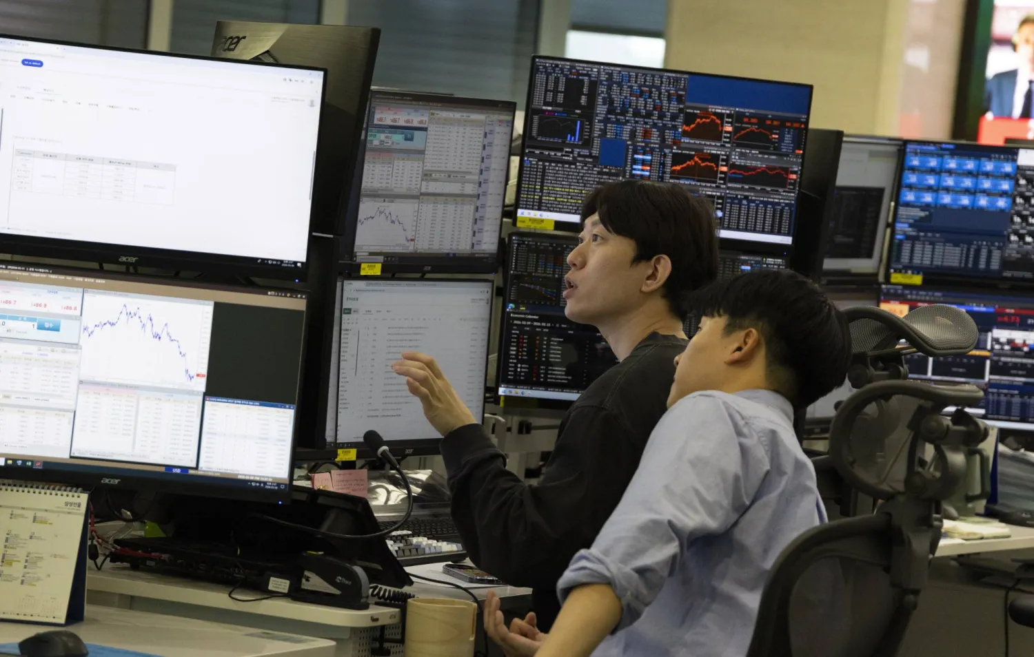 متداولون كوريون جنوبيون يعملون أمام شاشات تعرض مؤشرات الأسهم في بنك هانا في سيول (إ.ب.أ)