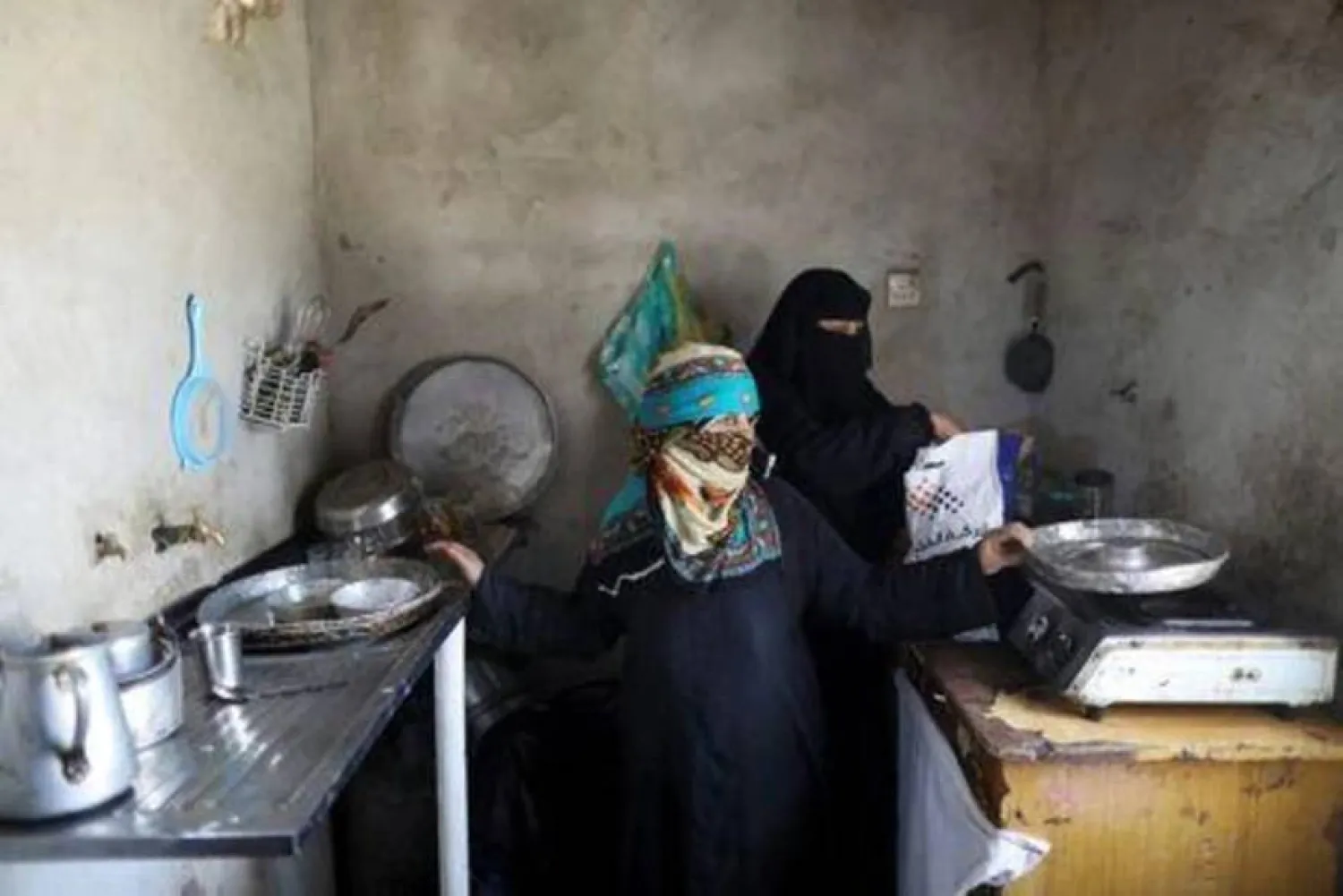 يمنية تعاين أطباق مطبخها الفارغة بسبب الأزمات المعيشية (رويترز)