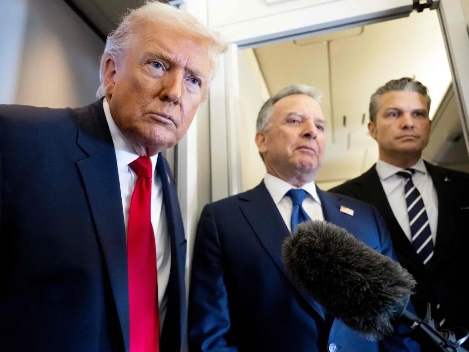 الرئيس الأميركي دونالد ترمب يتحدث إلى وسائل الإعلام وخلفه وزير الدفاع بيت هيغسيث (يميناً) والمبعوث الخاص ستيف ويتكوف (وسطاً) على متن طائرة الرئاسة «إير فورس ون» خلال رحلة من دوفر (أ.ف.ب)