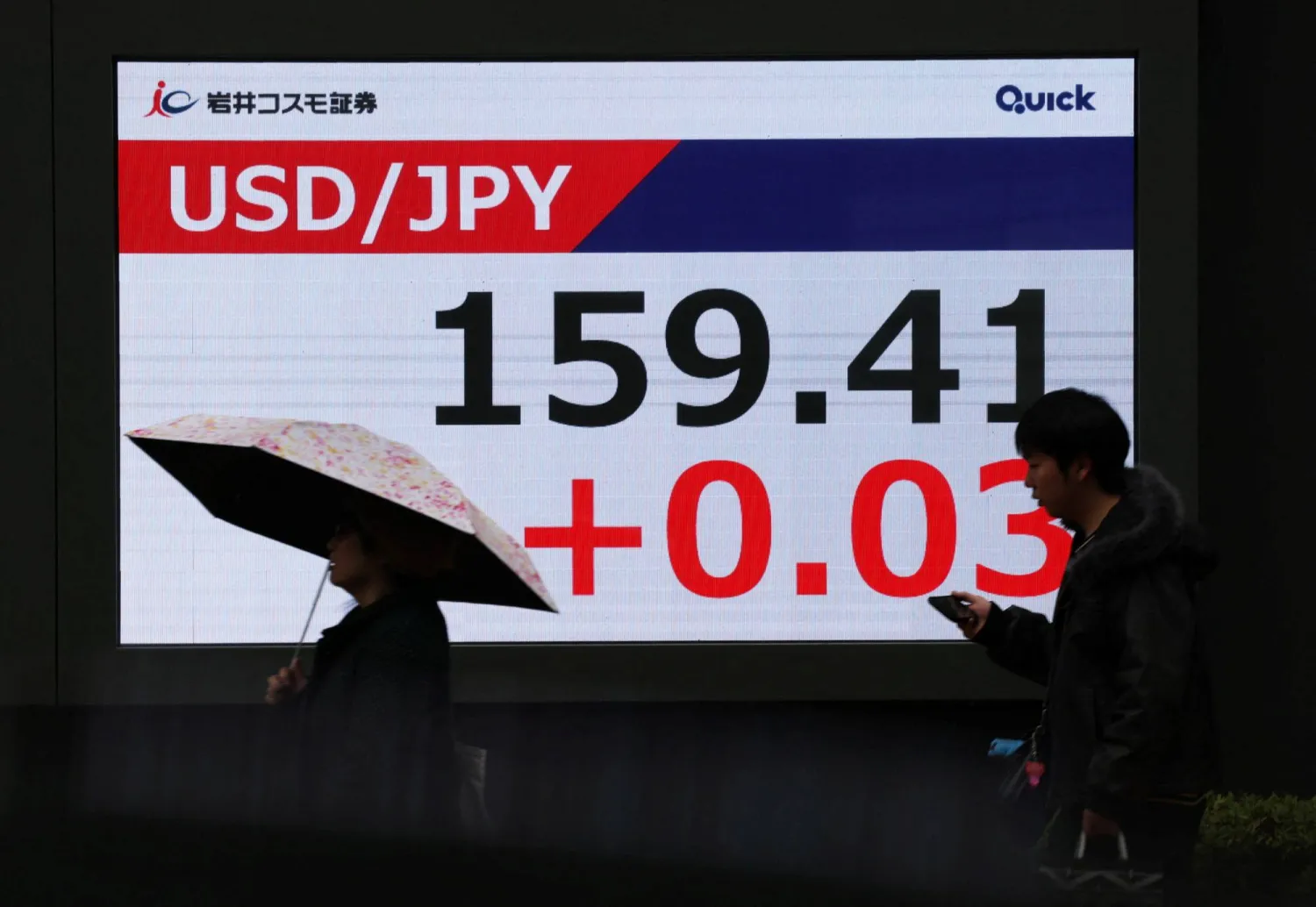 مشاة يمرون أمام شاشة تعرض حركة الين الياباني مقابل الدولار في وسط العاصمة اليابانية طوكيو (رويترز)