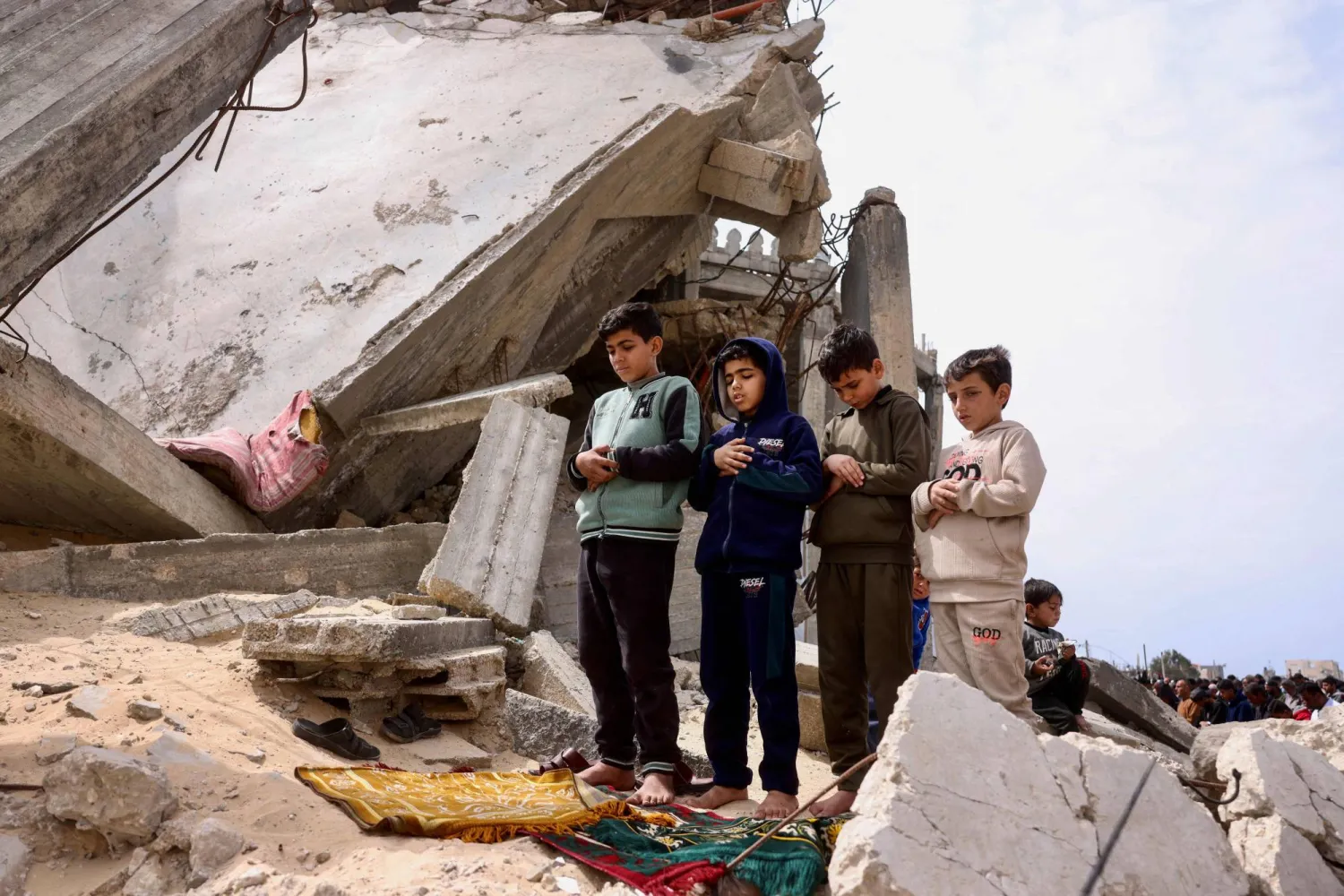 أطفال فلسطينيون يشاركون في صلاة الجمعة فوق أنقاض مسجد الطالباني الذي دمره القصف الإسرائيلي خلال الحرب في خان يونس جنوب قطاع غزة (أ.ف.ب)