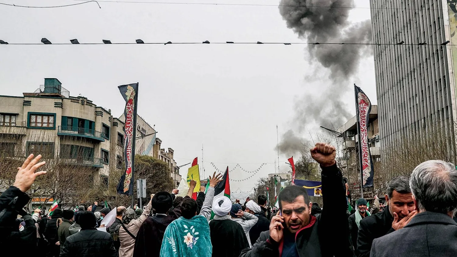  الدخان يتصاعد من موقع ضربة إسرائيلية في طهران بينما يحيي إيرانيون «يوم القدس» أمس (أ.ف.ب)