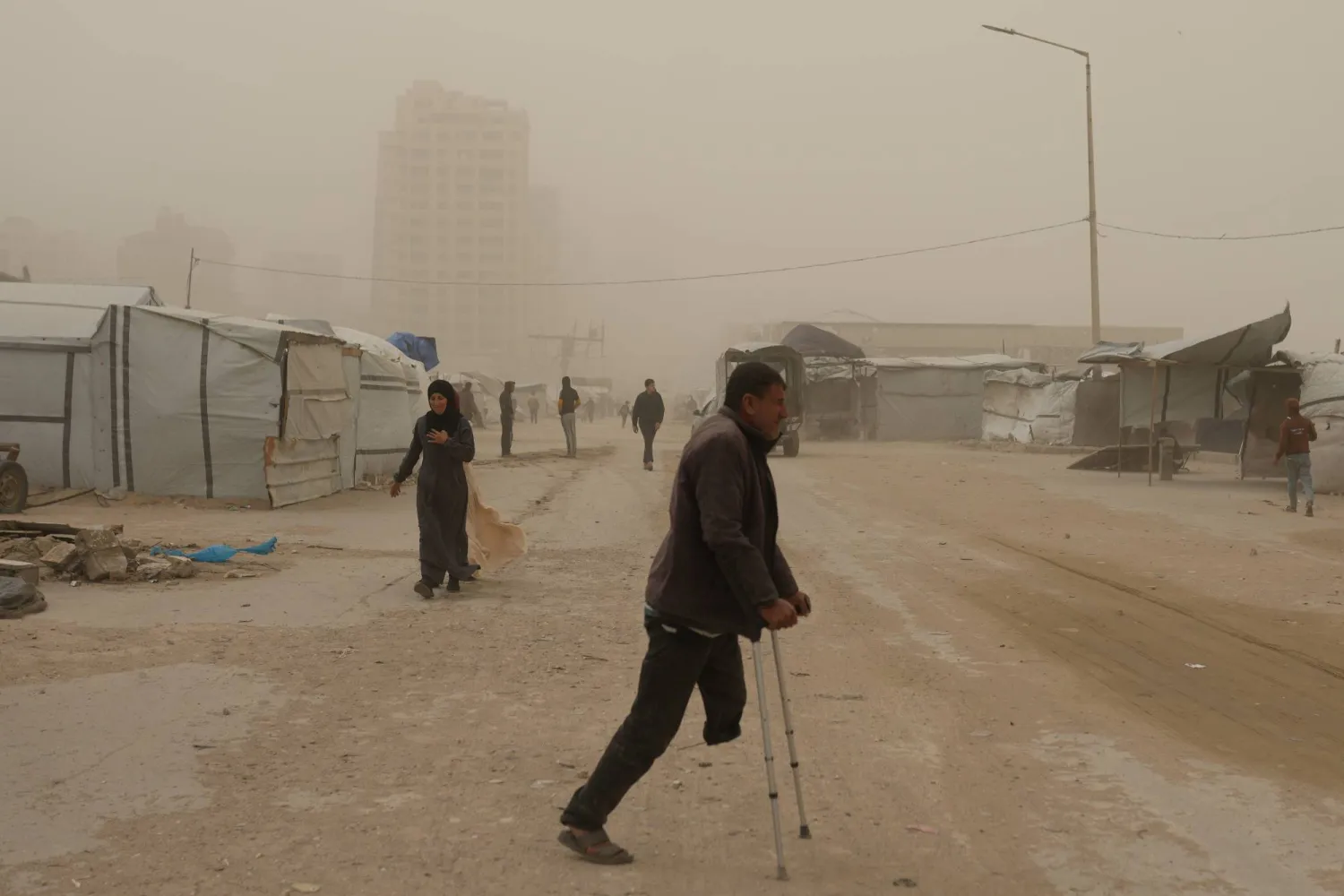 فلسطينيون يسيرون وسط العاصفة الرملية في خان يونس جنوب قطاع غزة السبت (أ.ب)