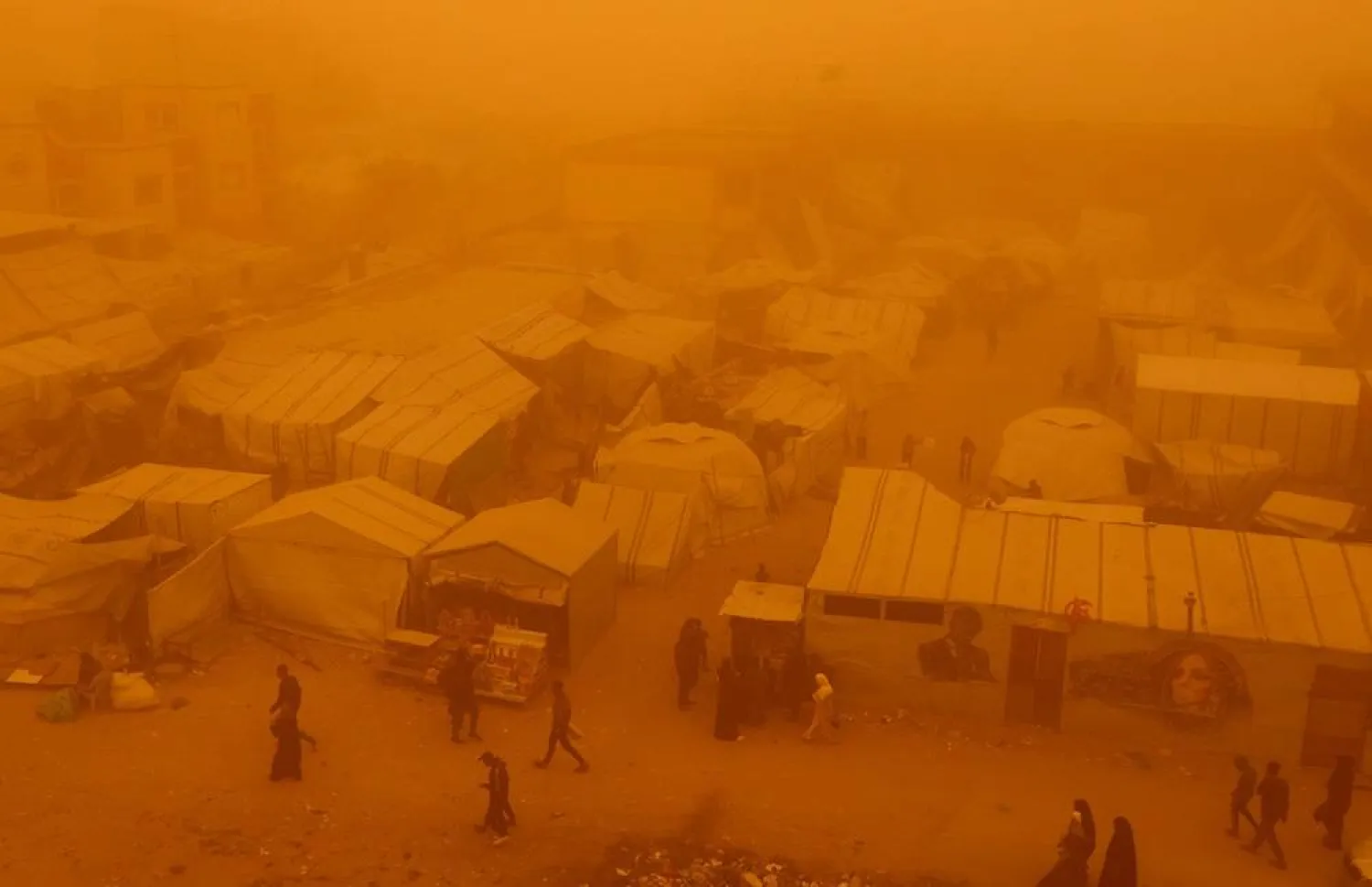  Palestinians walk amid a sandstorm in a tent camp sheltering Palestinians displaced during the two-year Israeli offensive, in Khan Younis in the southern Gaza Strip, March 14, 2026. (Reuters)