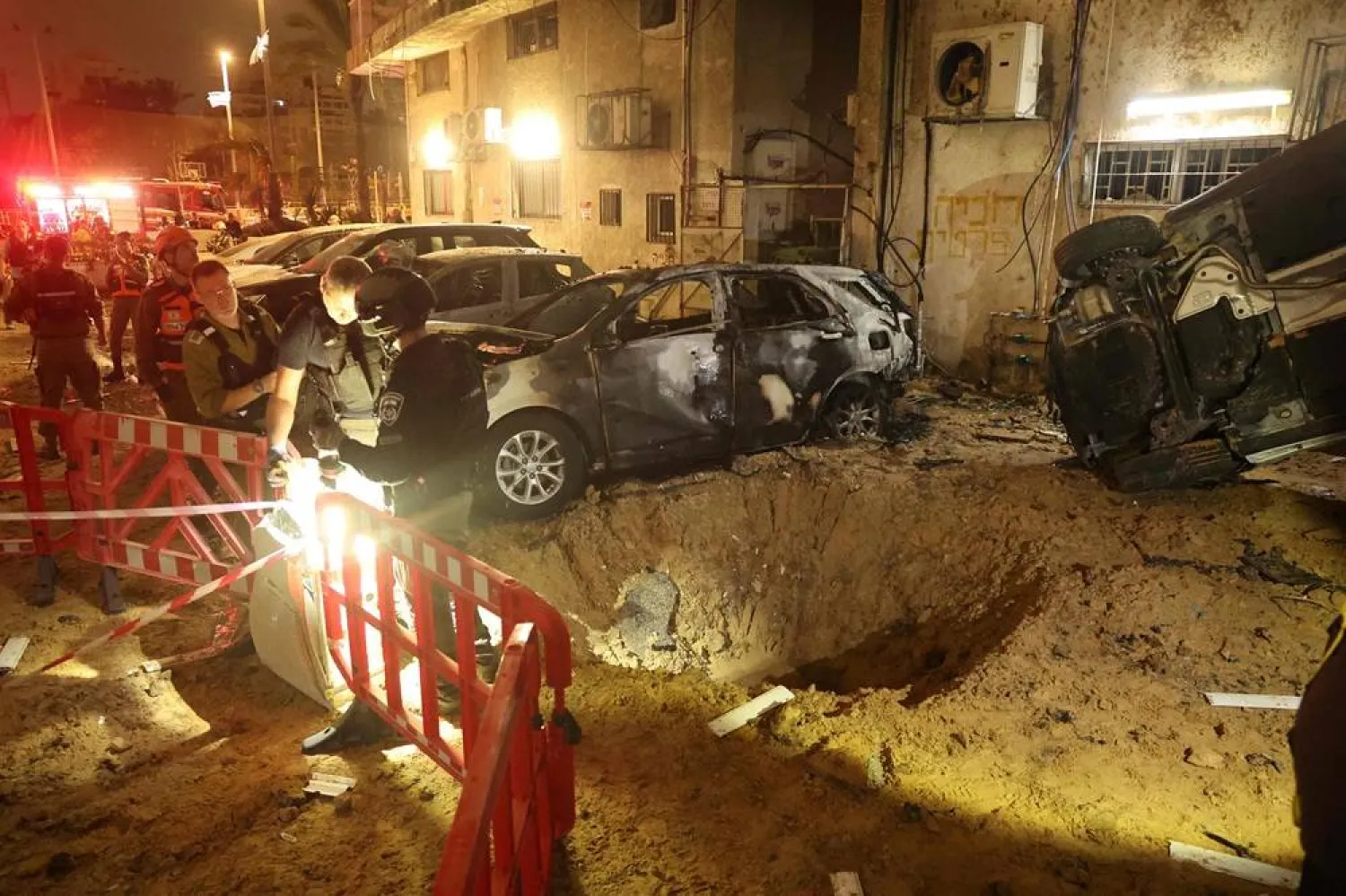 Israeli security forces check the damage to cars after a rocket strike in Holon, in the Tel Aviv District on March 15, 2026. (AFP)