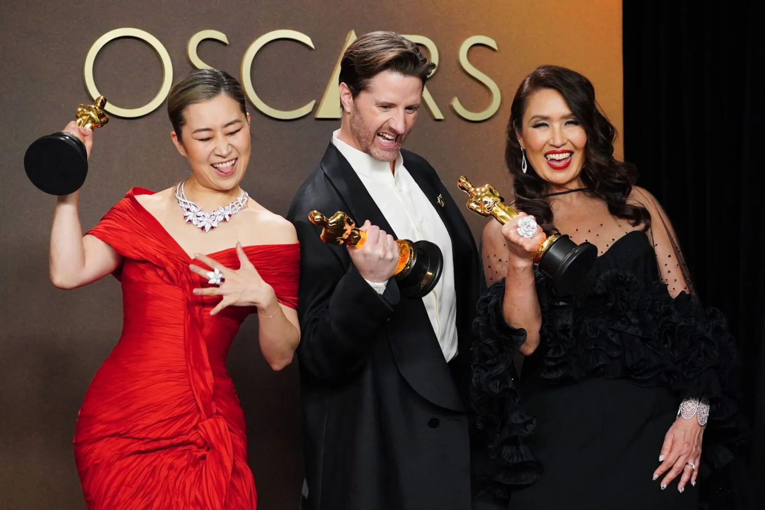 Maggie Kang, from left, Chris Appelhans, and Michelle L.M. Wong, winners of the award for animated feature film for "K-pop Demon Hunters," pose in the press room at the Oscars on Sunday, March 15, 2026, at the Dolby Theatre in Los Angeles. (Photo by Jordan Strauss/Invision/AP)