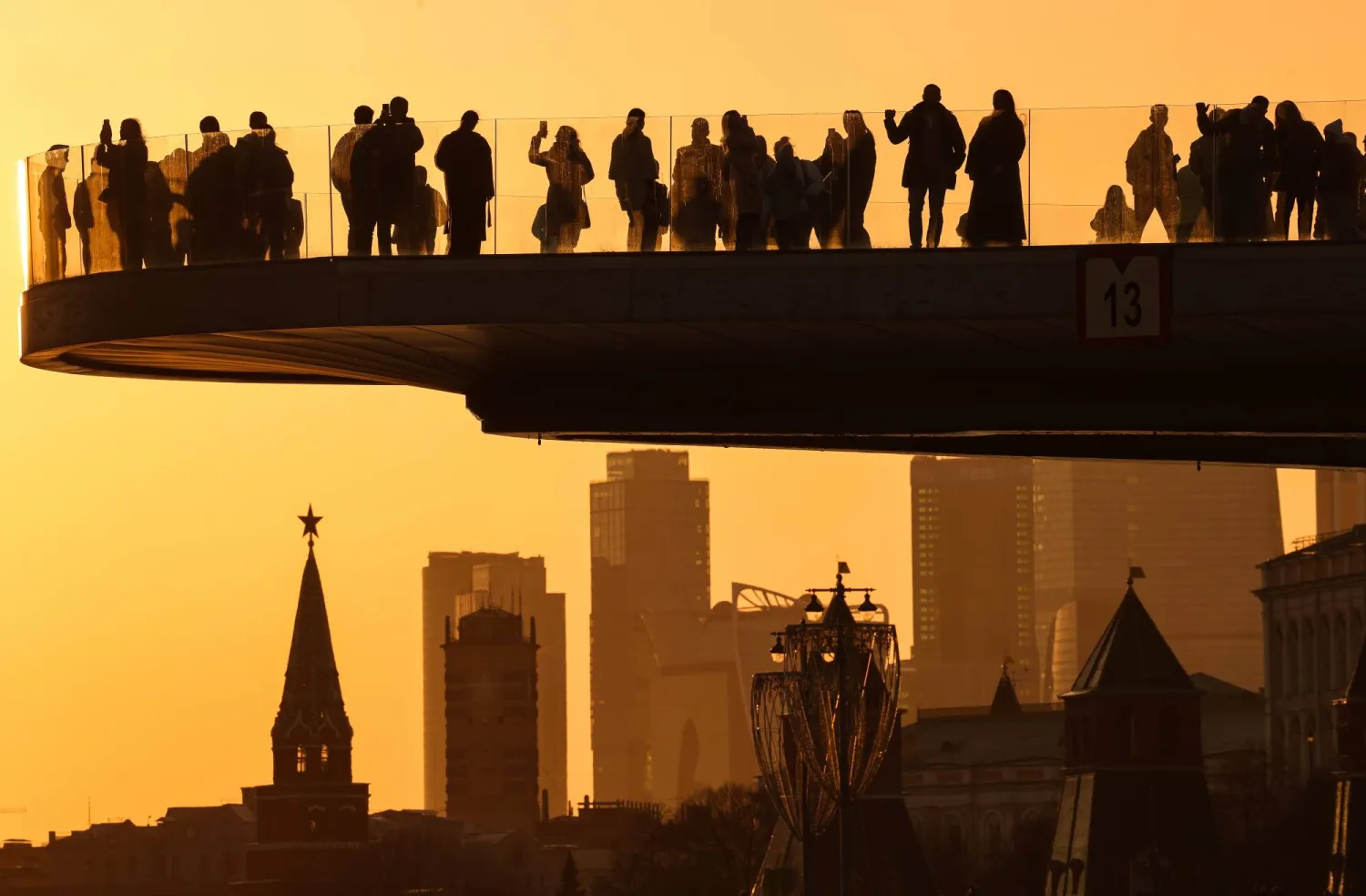 People gather on a bridge in front of the Kremlin during sunset on a warm and sunny day in Moscow, Russia, 13 March 2026. EPA/SERGEI ILNITSKY