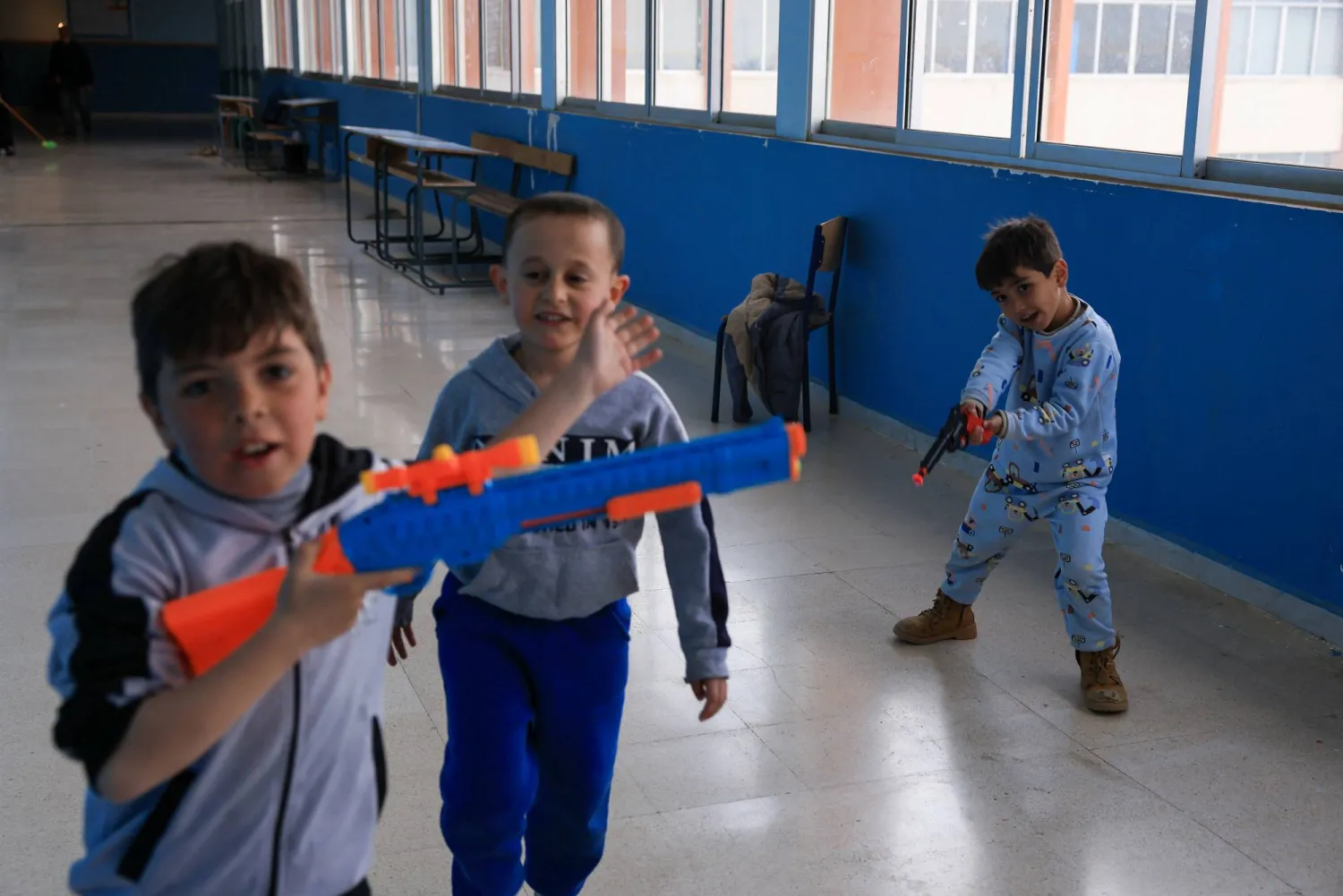 أطفال بمسدسات بلاستيكية في إحدى المدارس التي تحولت إلى مركز إيواء في بيروت (رويترز)