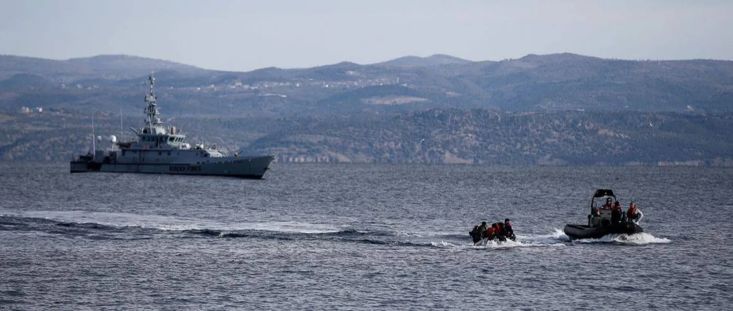 قارب إنقاذ يرافق قارباً صغيراً يحمل مهاجرين بينما تقوم سفينة تابعة لوكالة حرس الحدود الأوروبية «فرونتكس» بدورية في الخلفية قبالة جزيرة ليسبوس اليونانية (رويترز - أرشيفية)