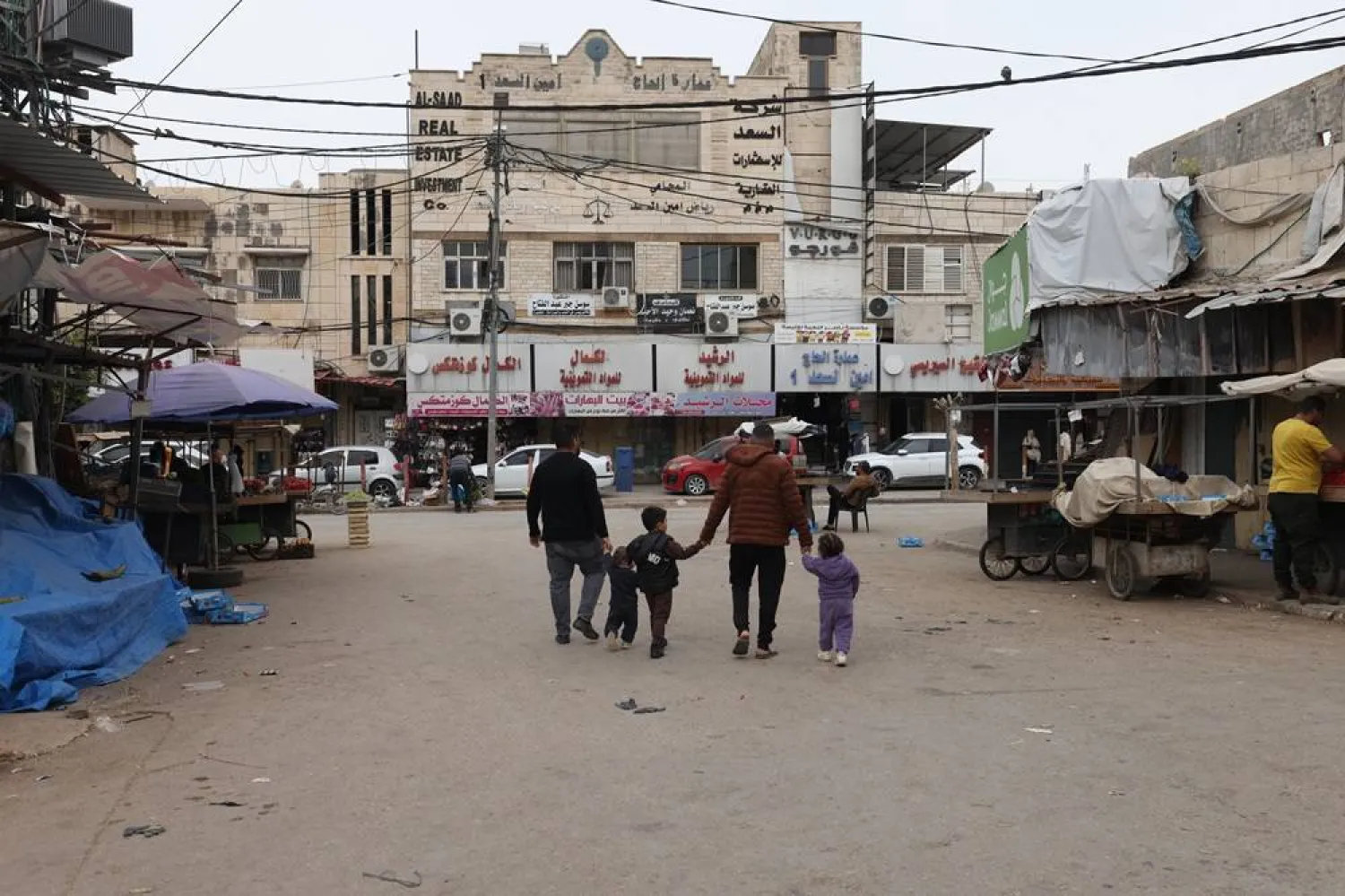 Palestinians men walk with children on the last Friday of the holy month of Ramadan in a market in the West Bank city of Jenin, 13 March 2026. (EPA)