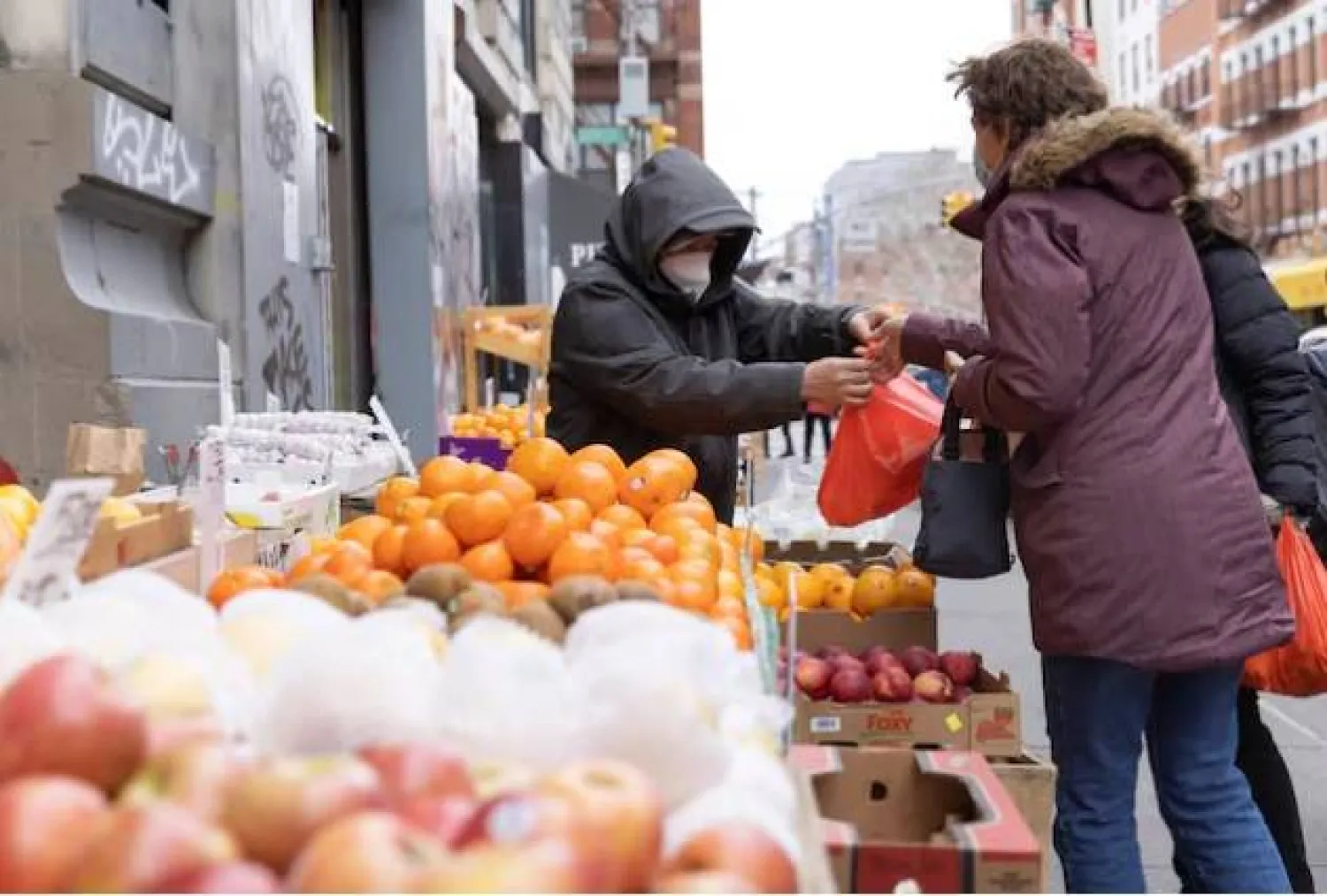 شخص يعمل في كشك لبيع الفواكه والخضراوات في مانهاتن بنيويورك (رويترز)