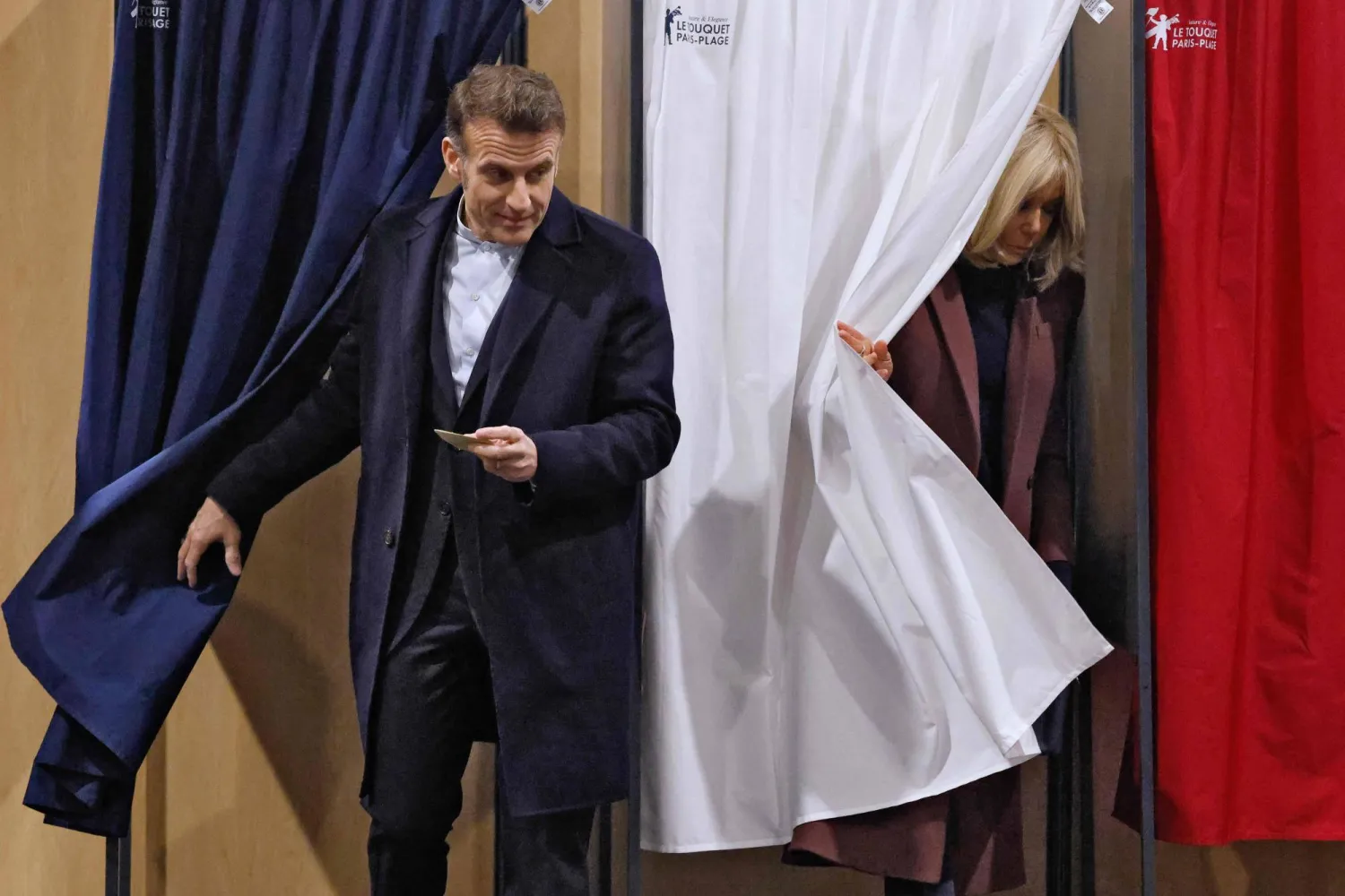 الرئيس الفرنسي إيمانويل ماكرون وزوجته بريجيت بعد اقتراعهما في الانتخابات المحلية بمدينة لو توكيه في شمال فرنسا (أ.ف.ب)