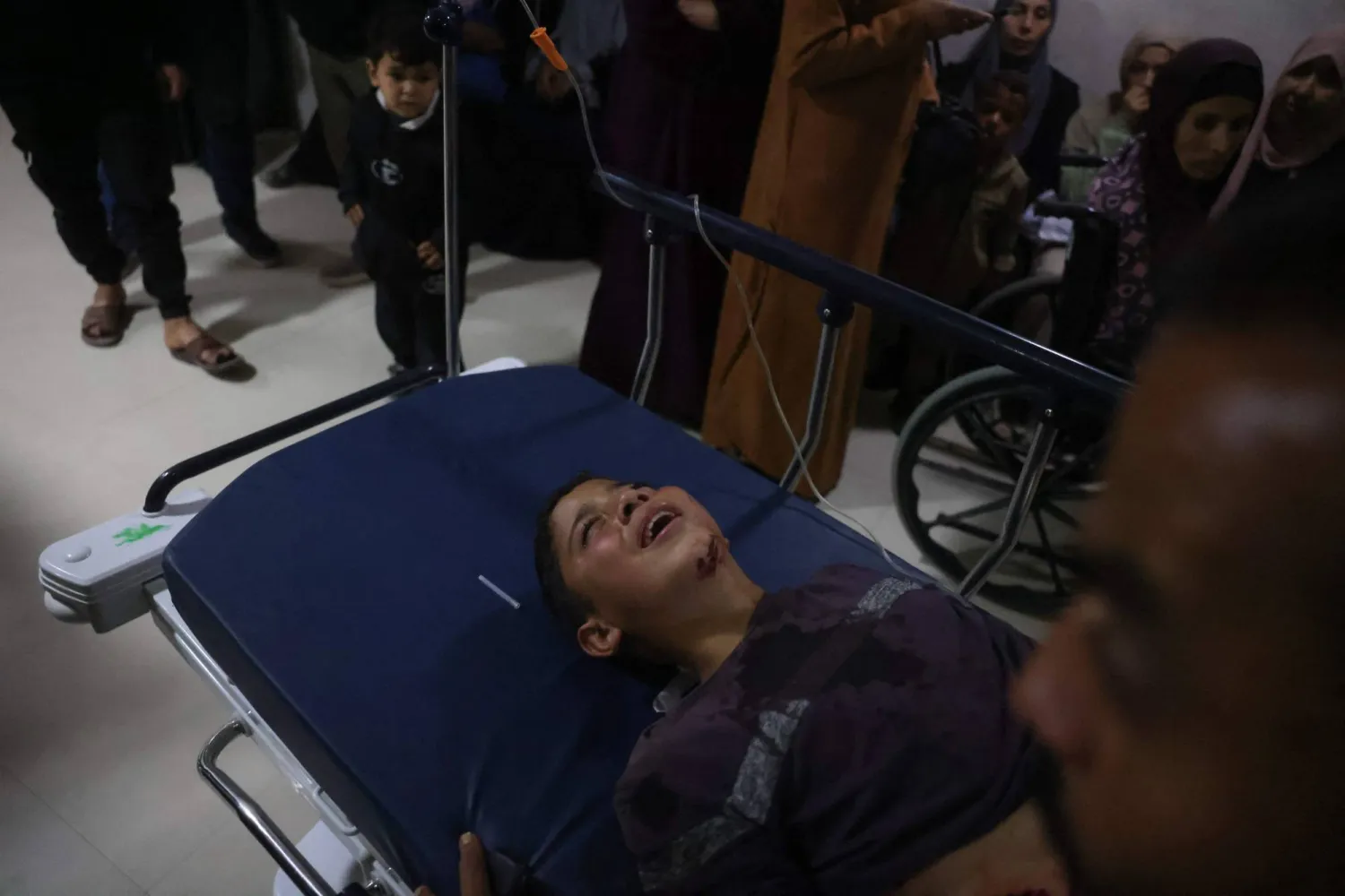 رجل يهرع حاملاً طفلاً يُقال إنه أصيب في غارة إسرائيلية إلى مستشفى ناصر بخان يونس الثلاثاء (أ.ب)