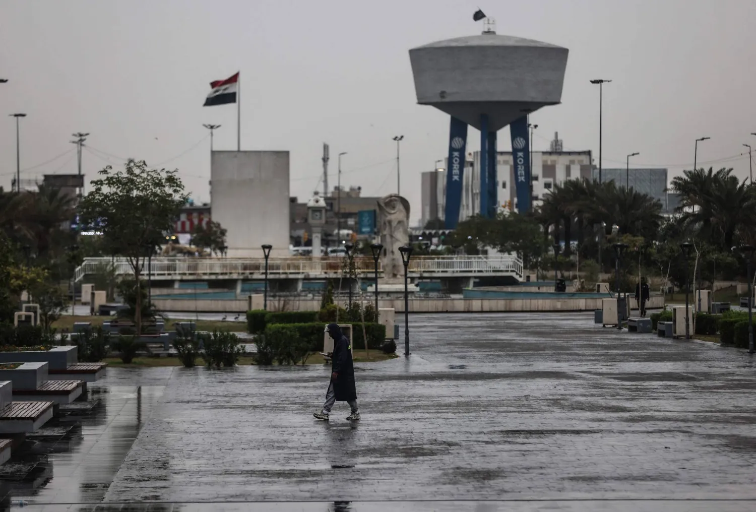 An Iraqi man walks through Al-Umma Park during rainfall in Baghdad on March 15, 2026. (AFP)