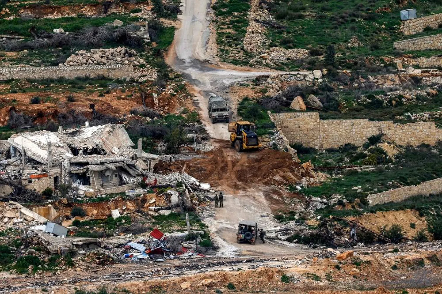 Israeli soldiers and a bulldozer conduct an operation in a southern Lebanese village along the border, as seen from a position in the Upper Galilee in northern Israel on March 18, 2026. (AFP)