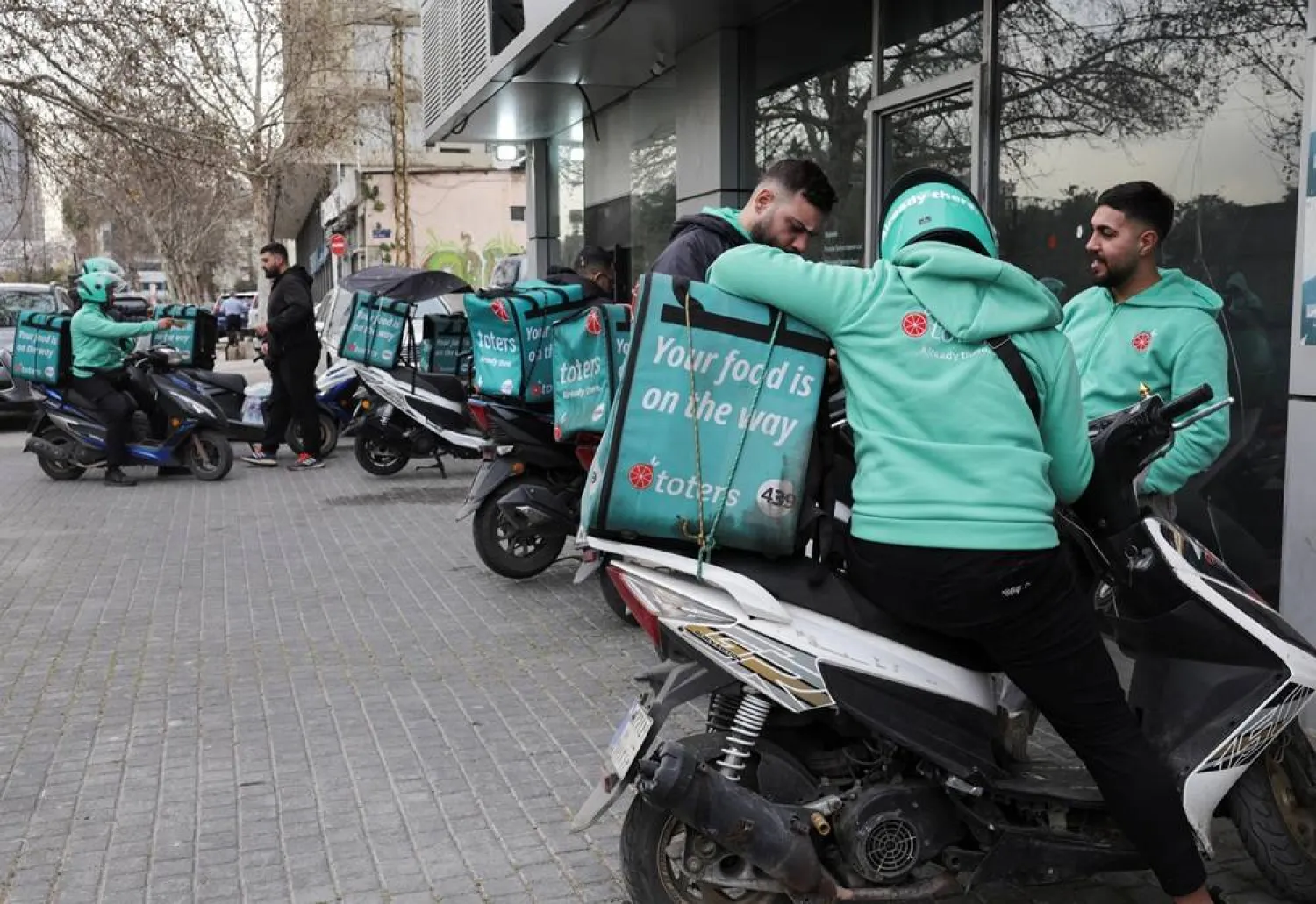  People who work as delivery drivers for the Toters delivery app stand outside a delivery center in Beirut, Lebanon, March 18, 2026. (Reuters)