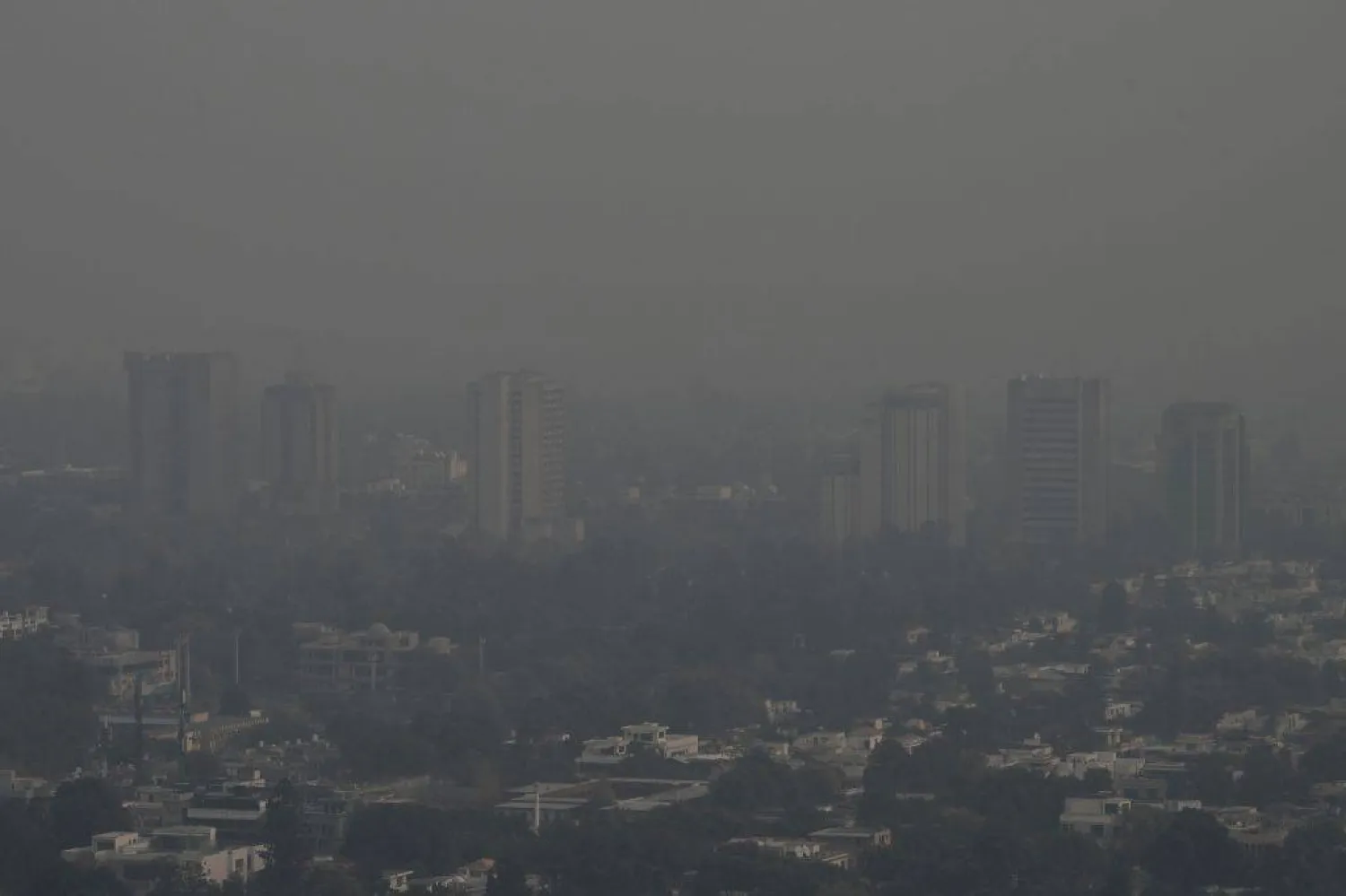 This picture taken on December 9, 2025, shows buildings engulfed in dense smog due to severe air pollution in Islamabad. (Photo by Aamir QURESHI / AFP)