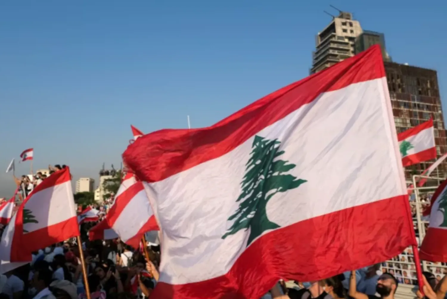 People carry national flags as they hold a moment of silence marking the one-year anniversary of Beirut's port blast, near the site of the explosion in Beirut, Lebanon August 4, 2021. REUTERS/Emilie Madi 