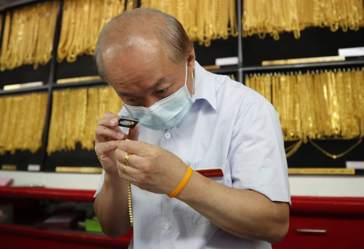 صائغ يفحص الحلي الذهبية في متجر للذهب في بانكوك (أ.ف.ب)