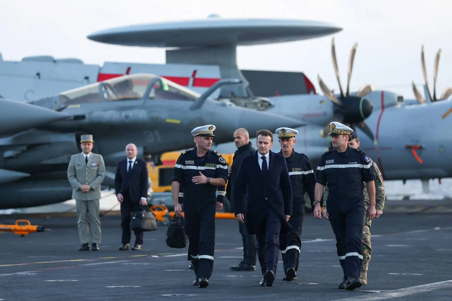 French President Emmanuel Macron (C) visits the French aircraft carrier Charles de Gaulle, deployed to the Mediterranean following Iranian drone strikes on Cyprus on the Mediterranean Sea, on March 9, 2026, on the sidelines of his trip to Cyprus to discuss regional security. (Photo by Gonzalo Fuentes / POOL / AFP)