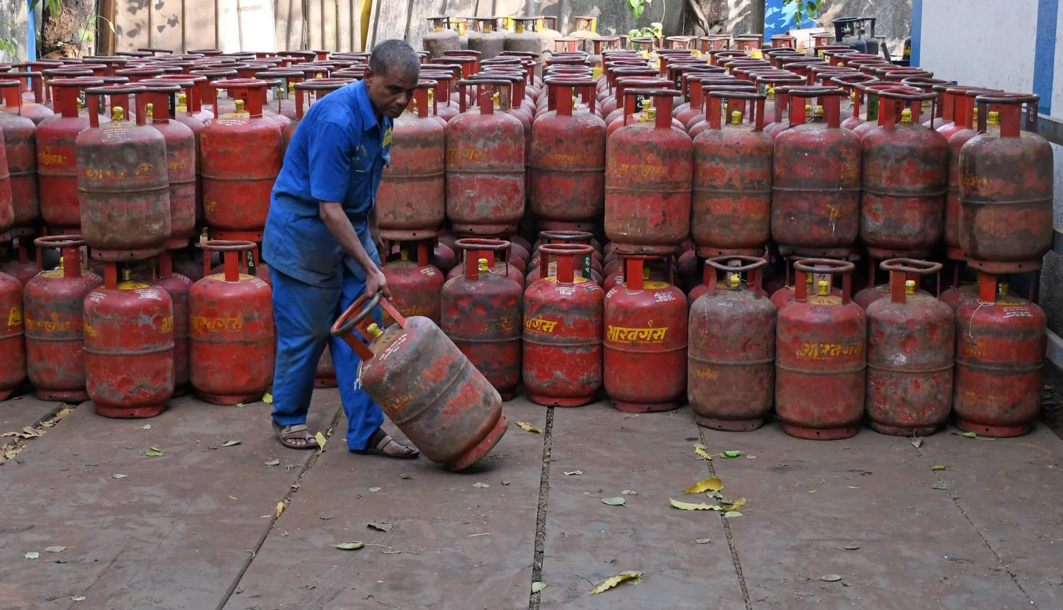 عامل ينقل أسطوانة غاز البترول المسال مملوءة من مستودع في مومباي (د.ب.أ)