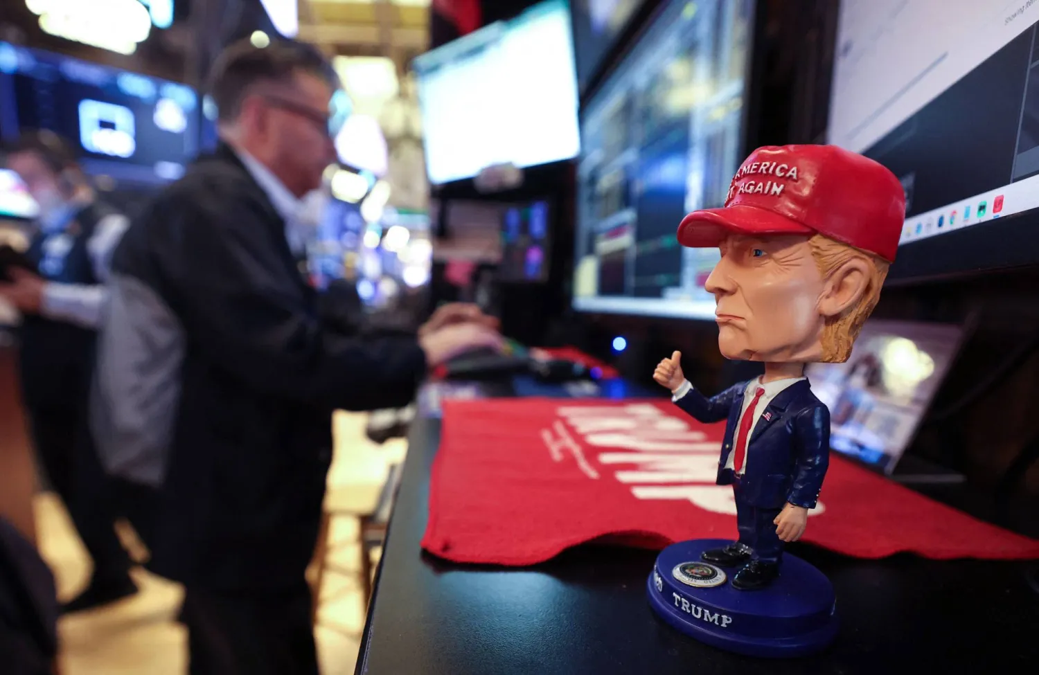 A bobble head depicting US President Donald Trump sits on a desk as traders works on the floor of the New York Stock Exchange (NYSE) at the opening bell in New York City, on April 14, 2025.  (Photo by TIMOTHY A. CLARY / AFP)