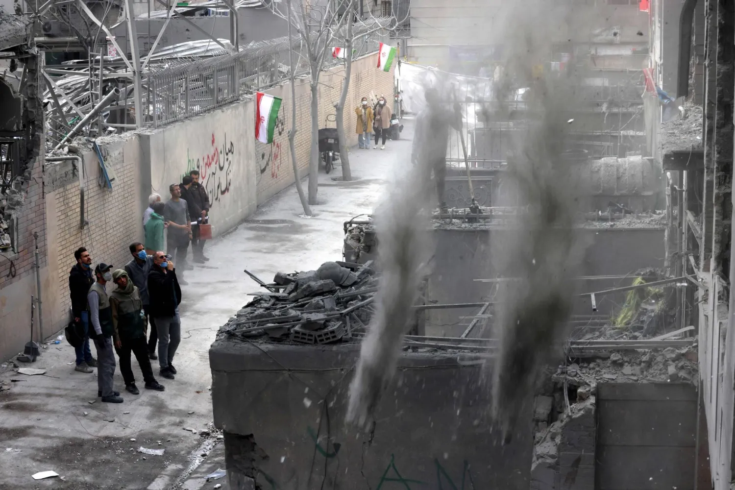 إيرانيون أمام مبنى متضرر من الحرب في العاصمة طهران (أ.ف.ب)