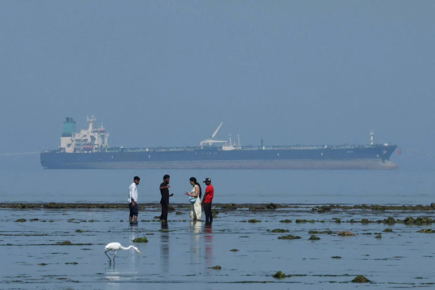FILE PHOTO: Tourists watch marine life, with the MT Desert Kite oil tanker carrying Russian oil in the background, at Narara Marine National Park in the Arabian Sea, Gujarat, India March 11 , 2026. REUTERS/Amit Dave/File Photo