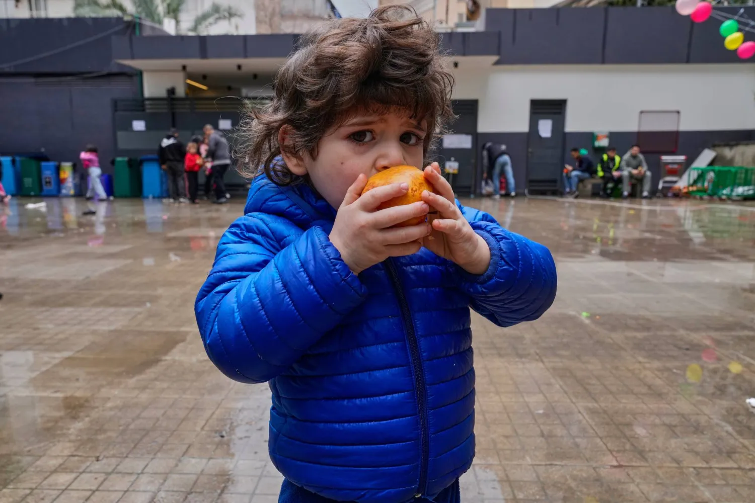 A displaced young girl who fled with her family Israeli airstrikes in southern Lebanon, eats an apple at a playground school that turned into a shelter in Beirut, Saturday, March 21, 2026. (AP Photo/Hussein Malla)