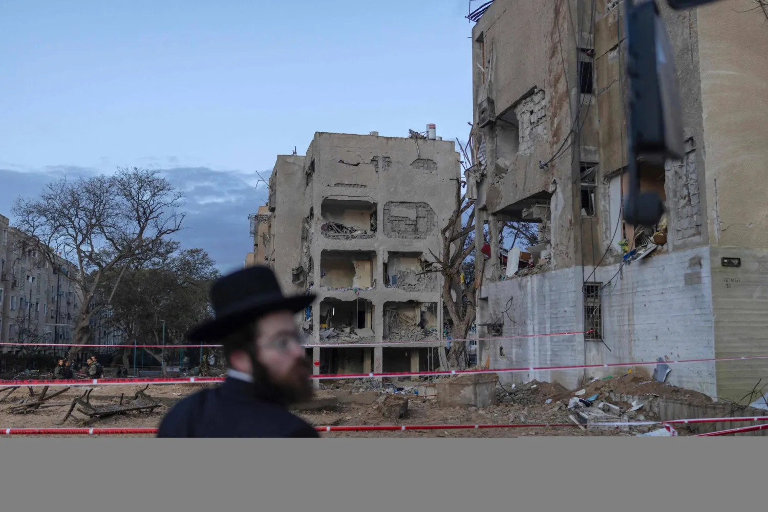 An Israeli Orthodox Jew inspects the site of an Iranian missile strike in Arad on March 22, 2026. (Photo by Ilia YEFIMOVICH / AFP) / 