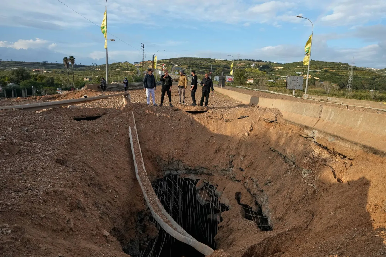 People inspect a crater following an Israeli airstrike that hit the Qasmiyeh Bridge near the coastal city of Tyre, Lebanon, Sunday, March 22, 2026. (AP Photo/Mohammad Zaatari)