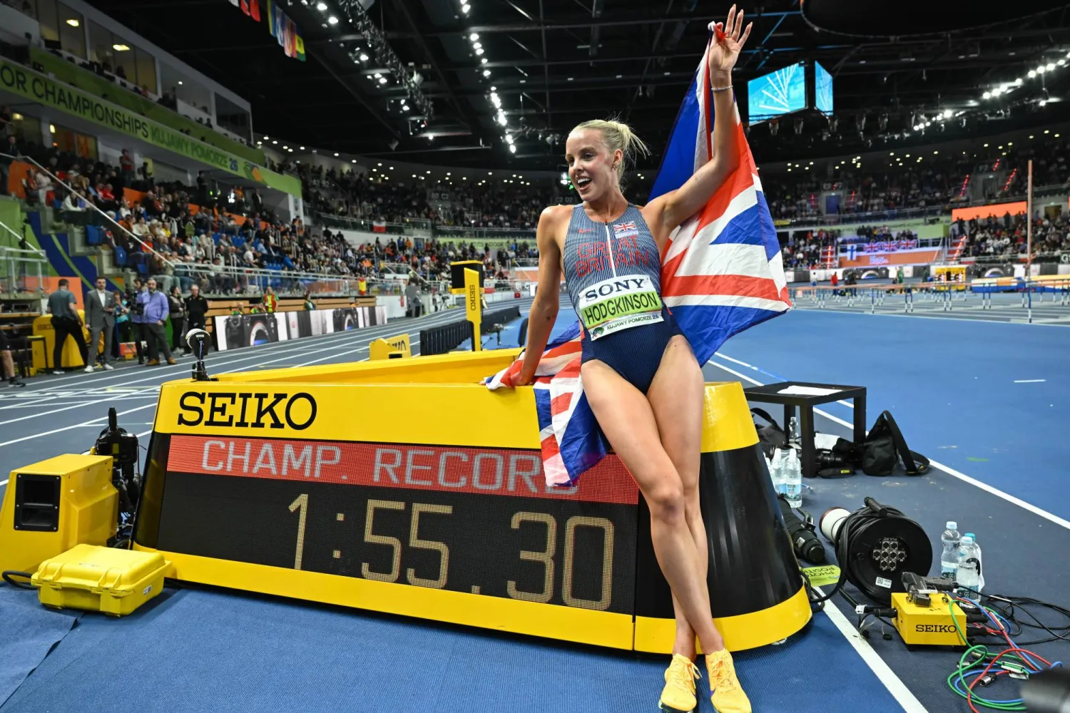 العداءة البريطانية كيلي هودجكينسون تحتفل بلقبها العالمي الأول داخل قاعة (إ.ب.أ)