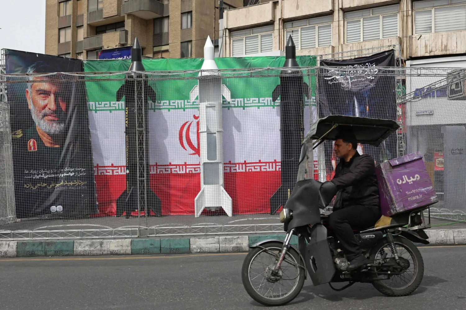 A motorist rides past the dummy models of Iranian missiles installed along the roadside at the Valiasr Square, in Tehran on March 22, 2026. (AFP)