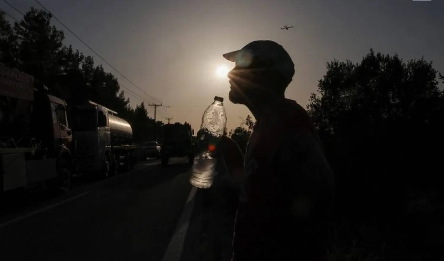 A volunteer holds a bottle of water as a wildfire burns in the village of Vati, on the island of Rhodes, Greece, July 26, 2023. REUTERS/Nicolas Economou/File photo