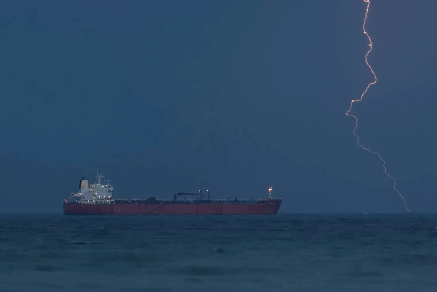 The tanker RARITY sits at anchor as lightning flashes in the distance, amid the US-Israeli conflict with Iran, off Sultan Qaboos Port in Muscat, Oman, March 21, 2026. REUTERS/Stelios Misinas