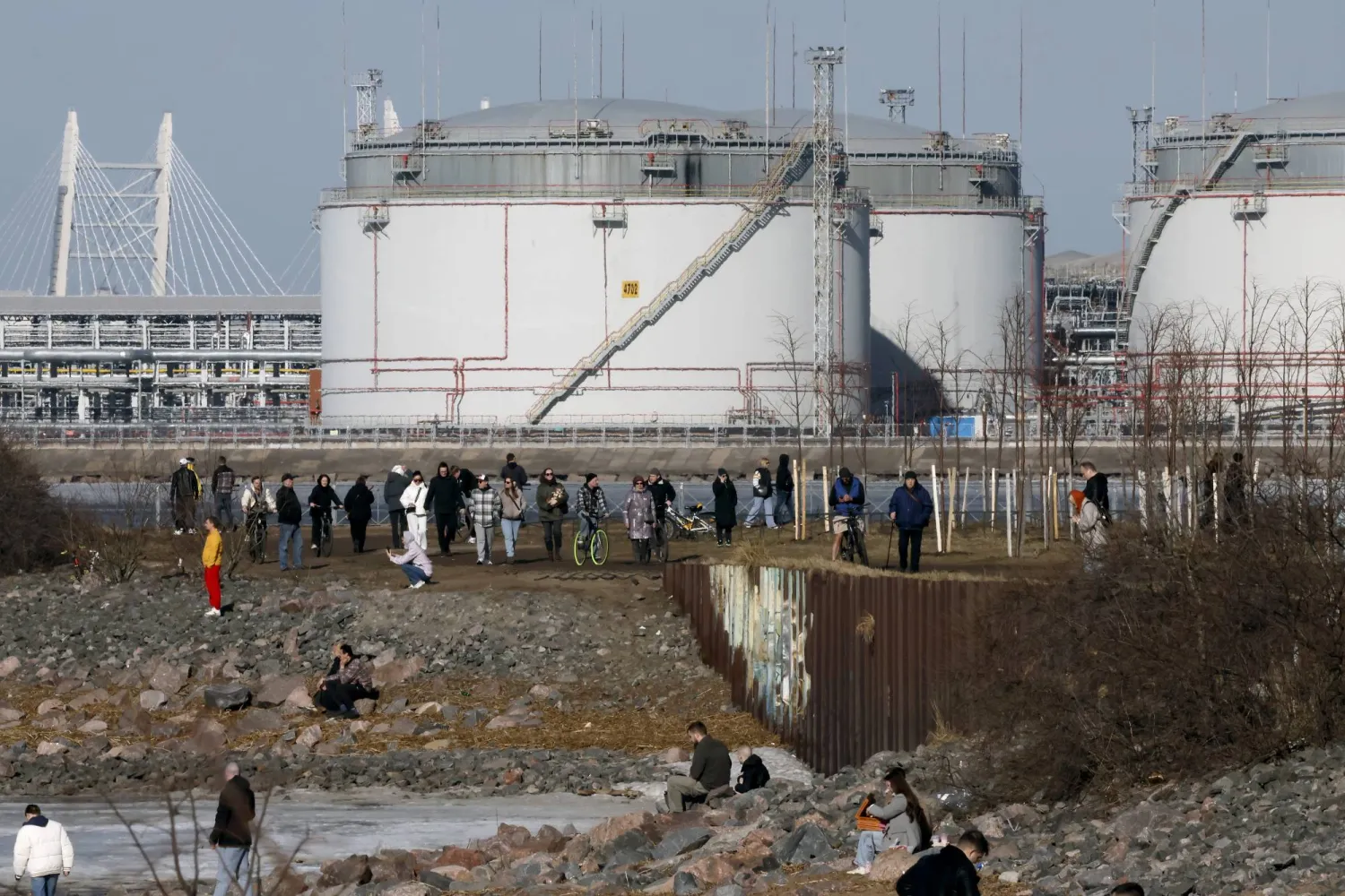 epa12841568 People walk on the shore of the Gulf of Finland with the St. Petersburg Oil Terminal in the background on a sunny day in St. Petersburg, Russia, 22 March 2026. Temperatures in St. Petersburg, Russia's second largest city, reached eleven degrees Celsius.  EPA/ANATOLY MALTSEV