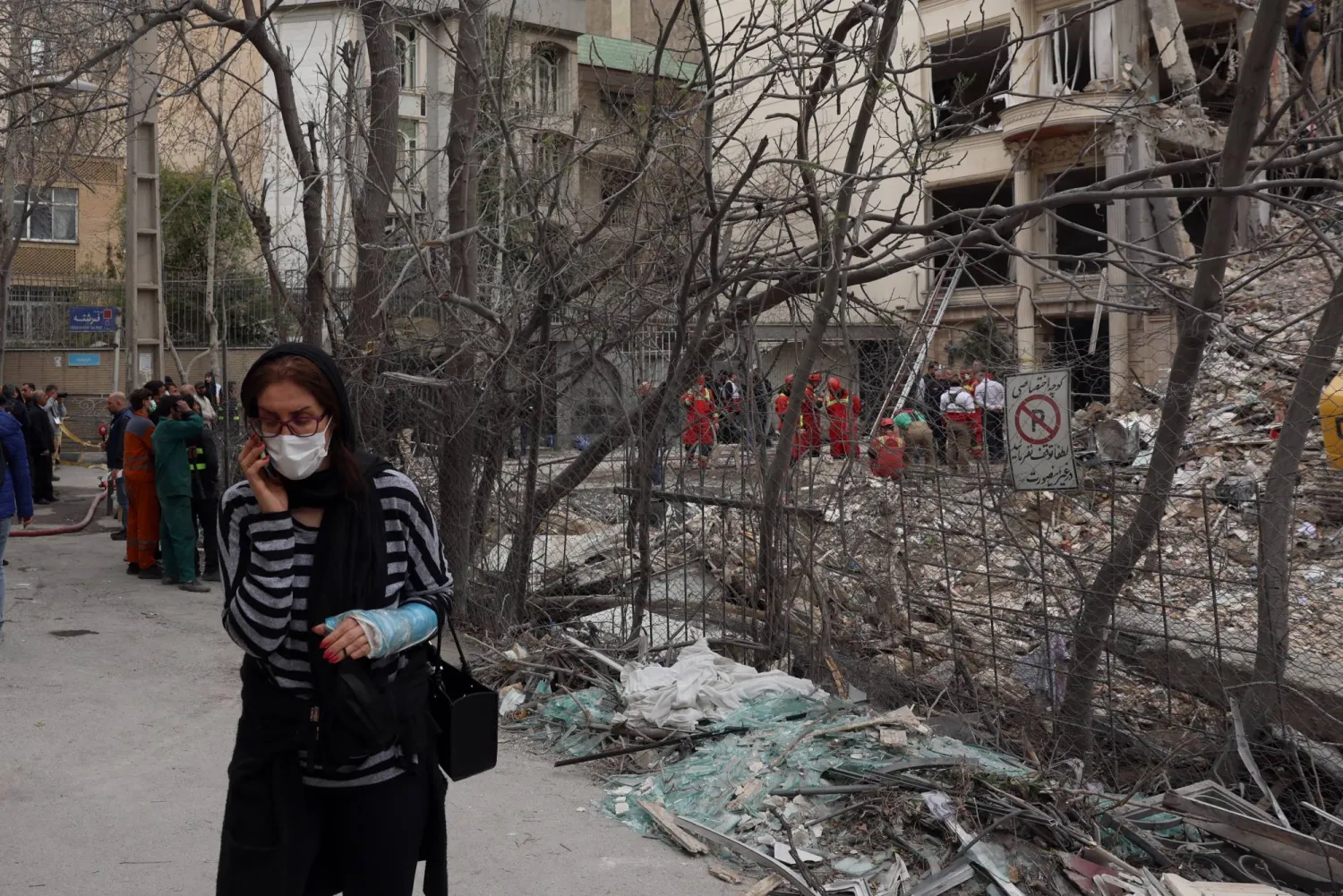 سيدة إيرانية مصابة تسير بجانب مبنى تضرر جراء الغارات الأميركية - الإسرائيلية شمال طهران أمس (إ.ب.أ)