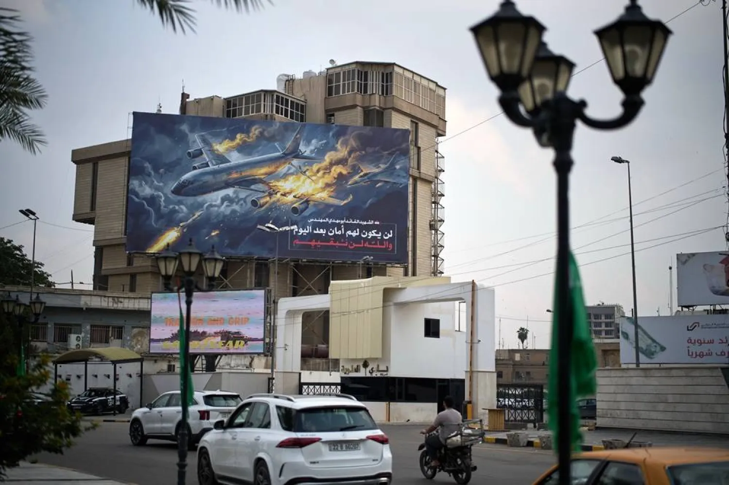  A billboard displays an image depicting a US Air Force airplane in flames, the name of the Iraqi deputy PMF leader Abu Mahdi al-Muhandis who was killed in a US strike in 2020, and words that read in Arabic, "They will no longer have safety. By God, we will not spare them", in Baghdad, Iraq, Monday, March 23, 2026. (AP) 