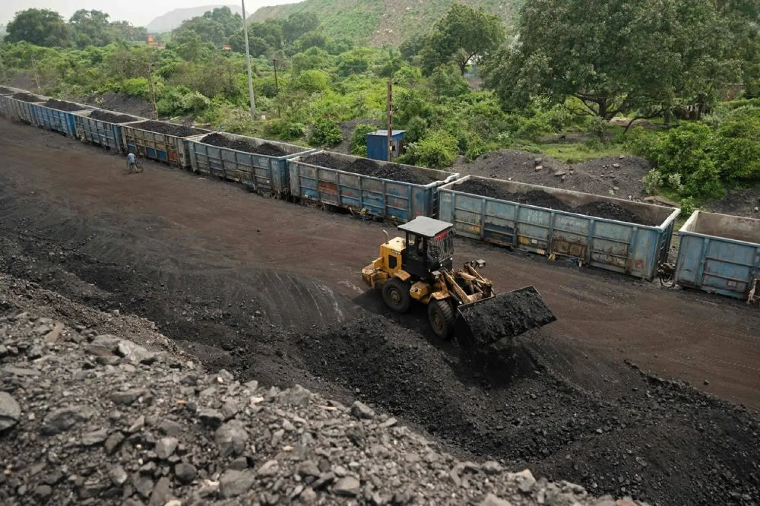 A worker operates a wheel loader to convey heaps of raw coal into train carriages, excavated from an open-cast mine on the outskirts of Dhanbad, in India's Jharkhand state on August 13, 2025. (AFP)