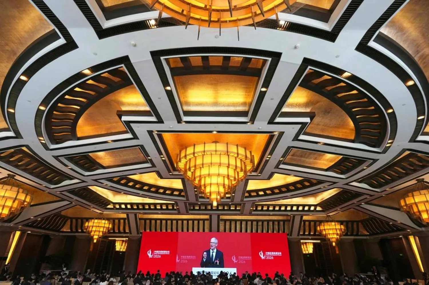  Apple CEO Tim Cook is seen on a big screen live broadcasting his speech at the opening of the China Development Forum 2026 held at the Diaoyutai State Guesthouse in Beijing on March 22, 2026. (AFP) 