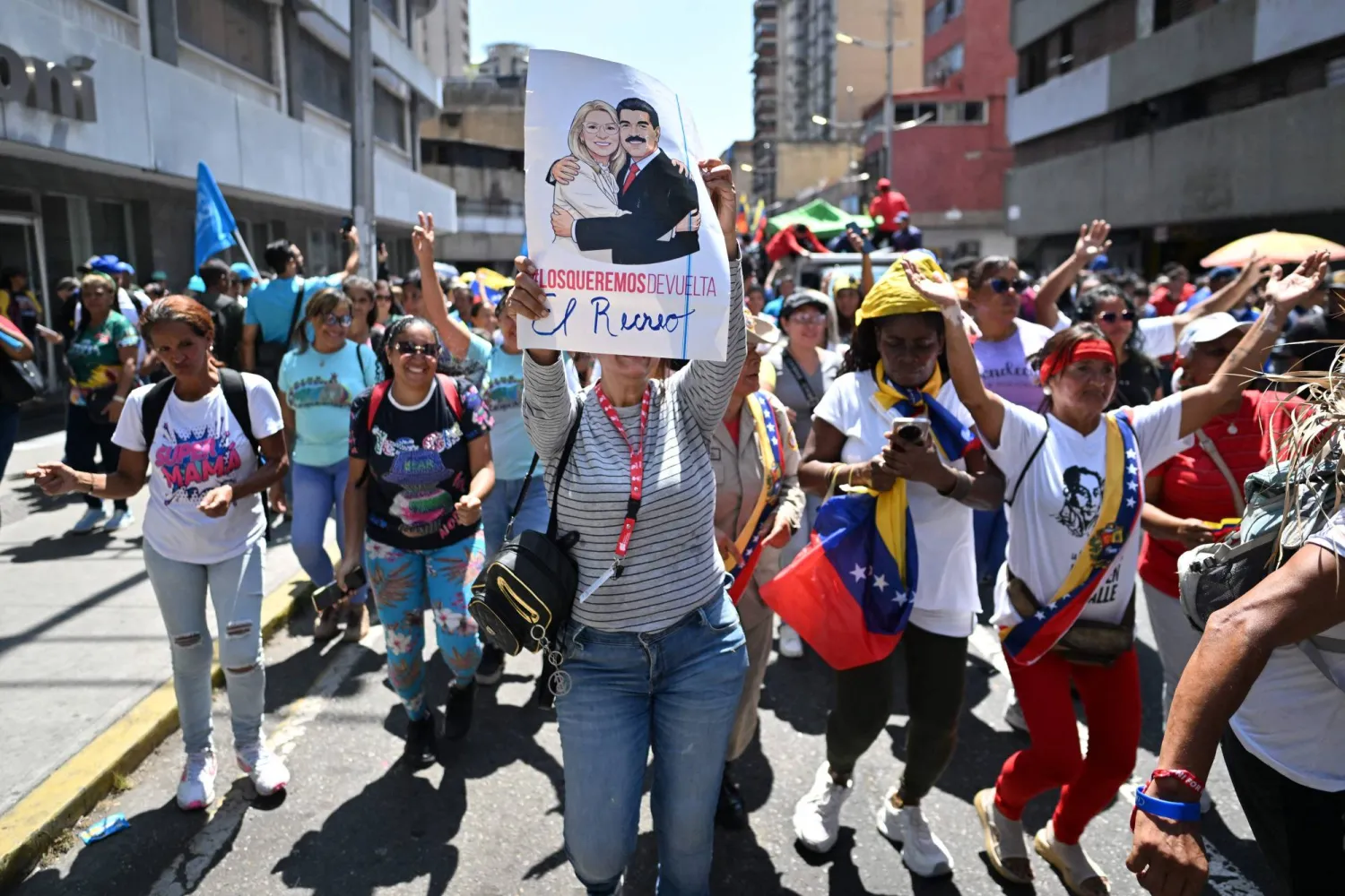  A woman holds up a poster depicting Venezuelan deposed President Nicolas Maduro and his wife, Cilia Flores, during a march demanding the complete lifting of US sanctions in Caracas on March 23, 2026. (AFP) 
