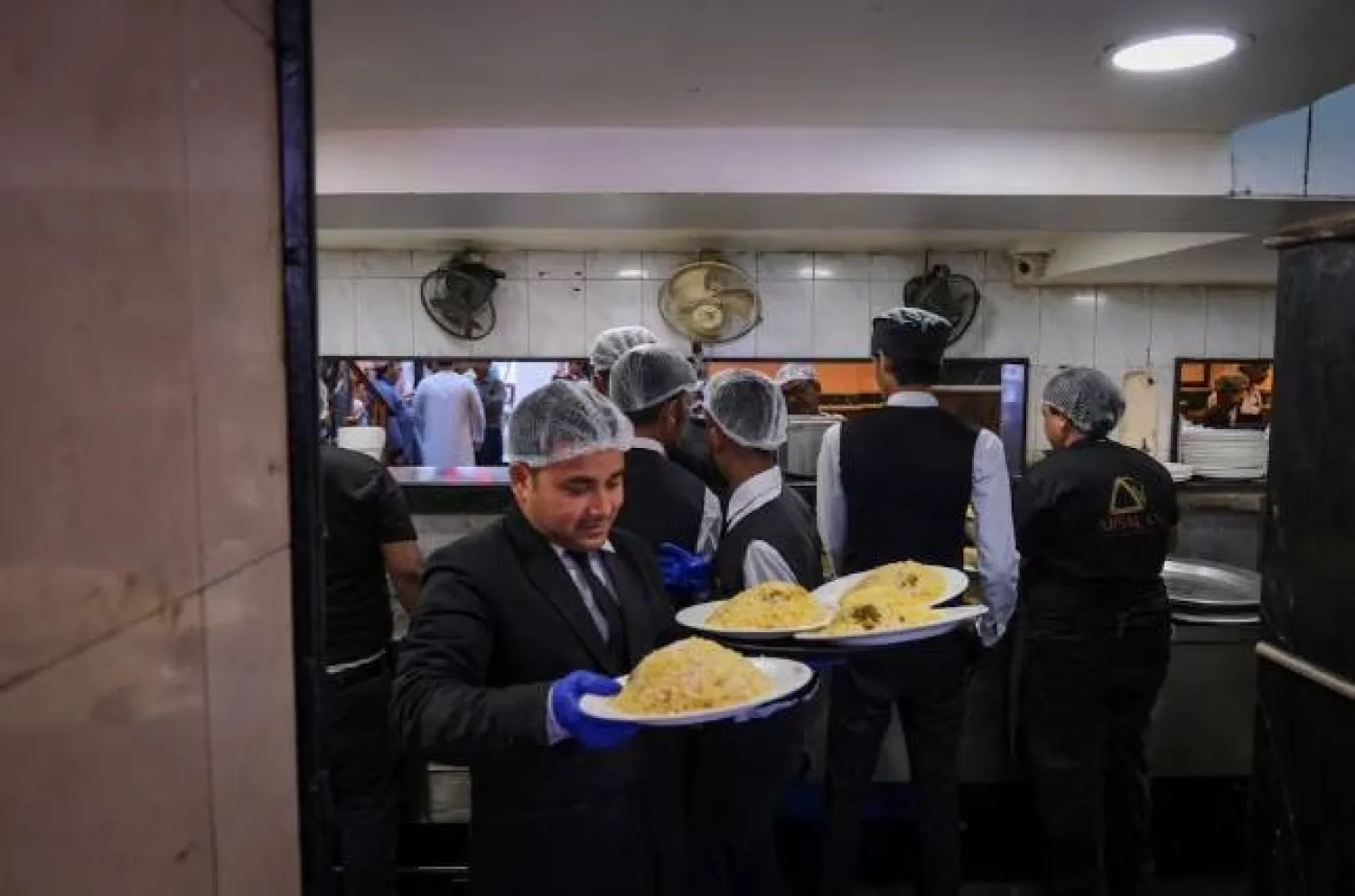 نادل يحمل طبق برياني لتقديمه للزبائن داخل مطعم في كولكاتا بالهند (رويترز)