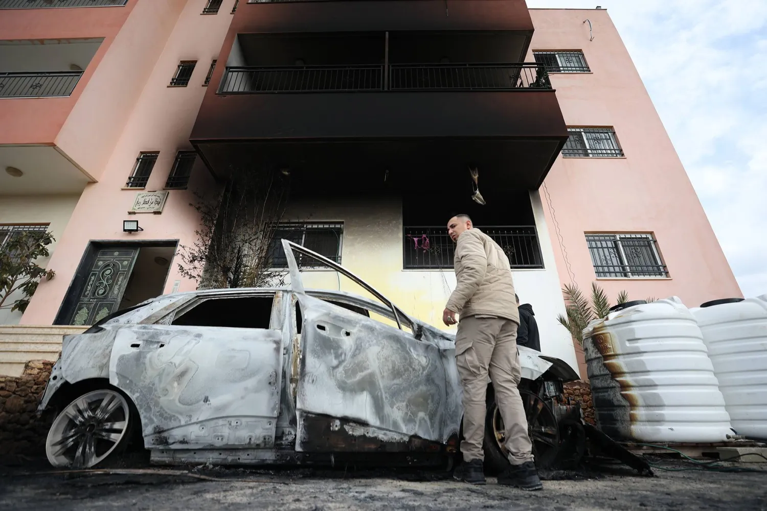 فلسطينيون يتفقدون الأضرار في قرية دير الحطب بالضفة الغربية بعد هجوم مستوطنين (إ.ب.أ)