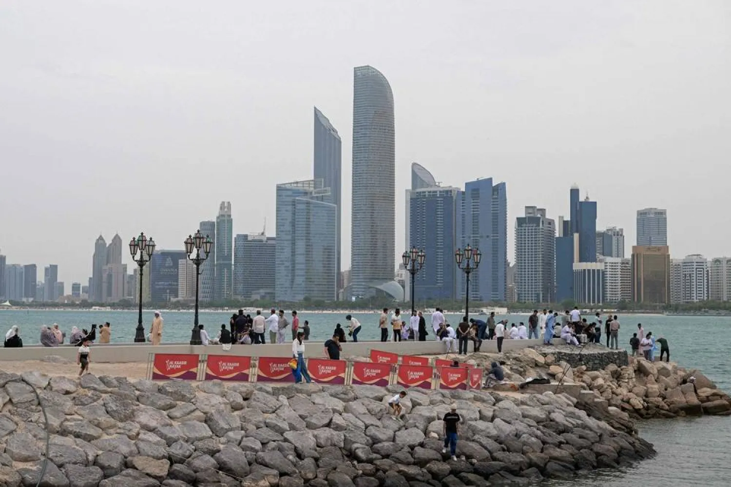  People sit along the corniche area on the occasion of Eid al-Fitr, marking the end of the holy month of Ramadan, in Abu Dhabi on March 20, 2026. (AFP) 