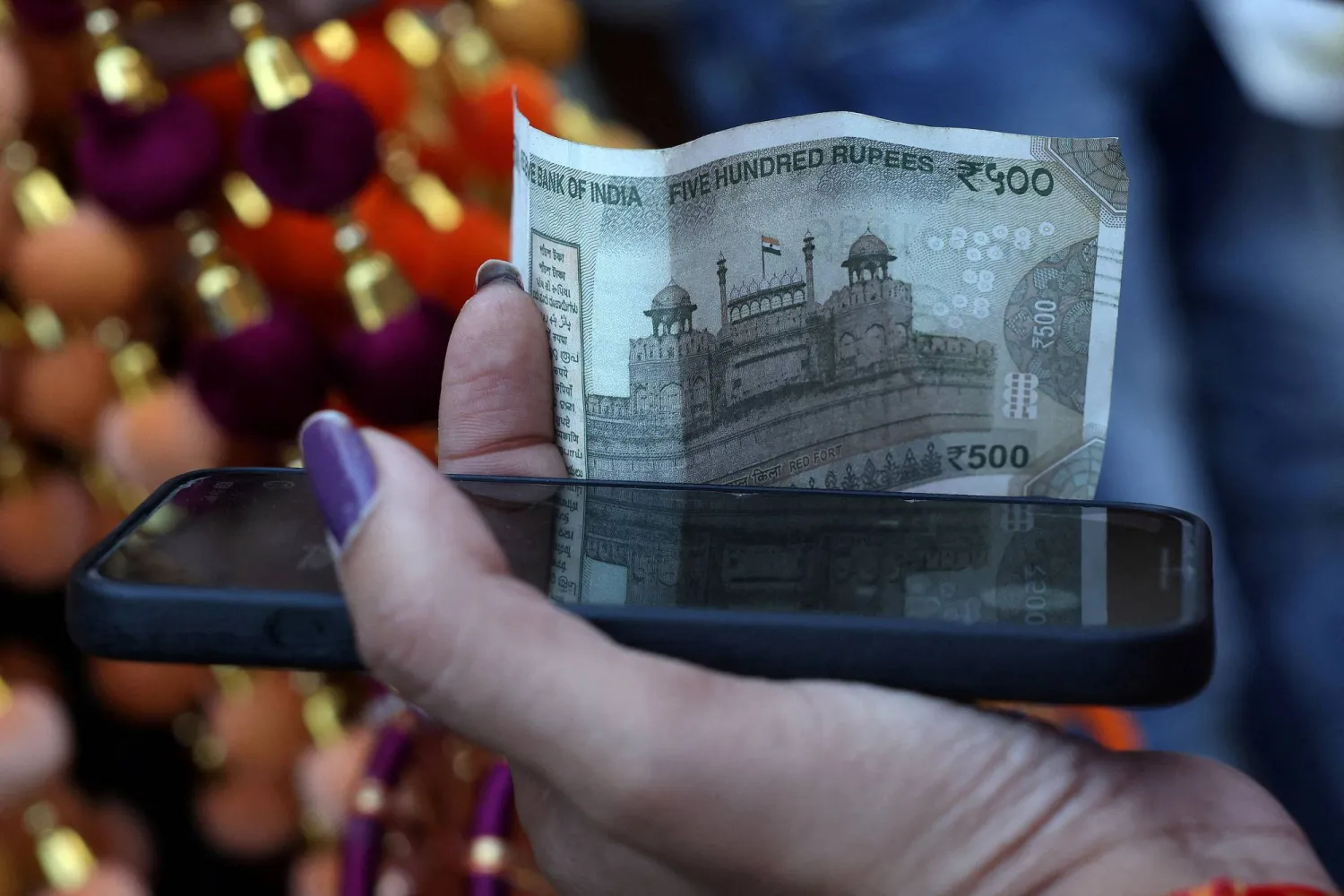 امرأة تحمل ورقة نقدية من فئة 500 روبية في الأحياء القديمة بدلهي (رويترز)