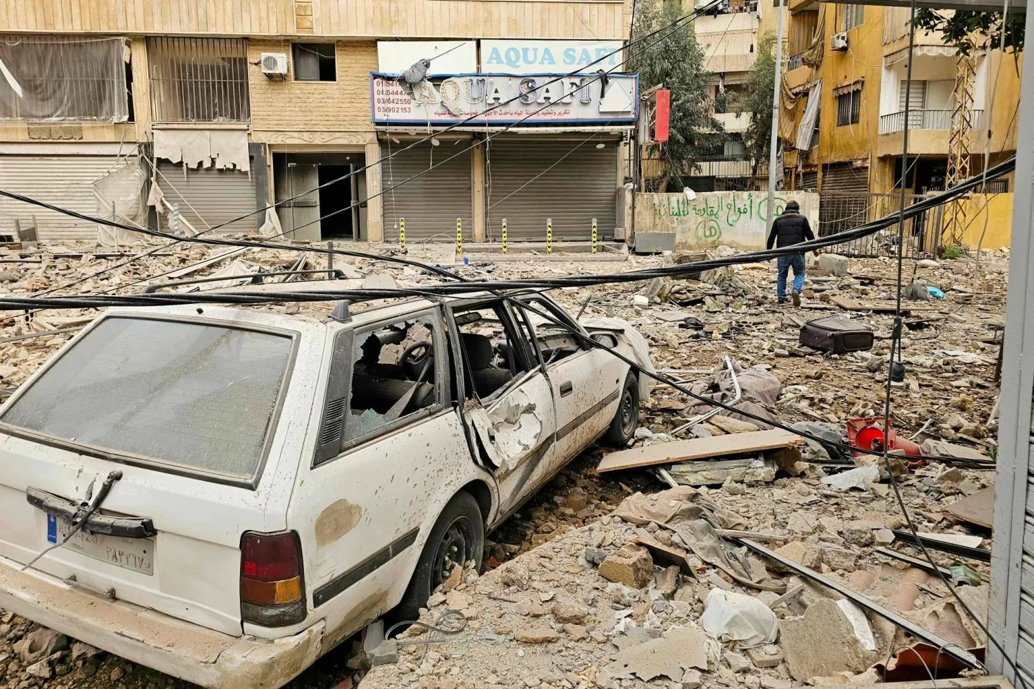 رجل يسير في شارع تتناثر به مخلفات البناء بموقع غارة جوية إسرائيلية استهدفت حياً بالضواحي الجنوبية لبيروت (أ.ف.ب)