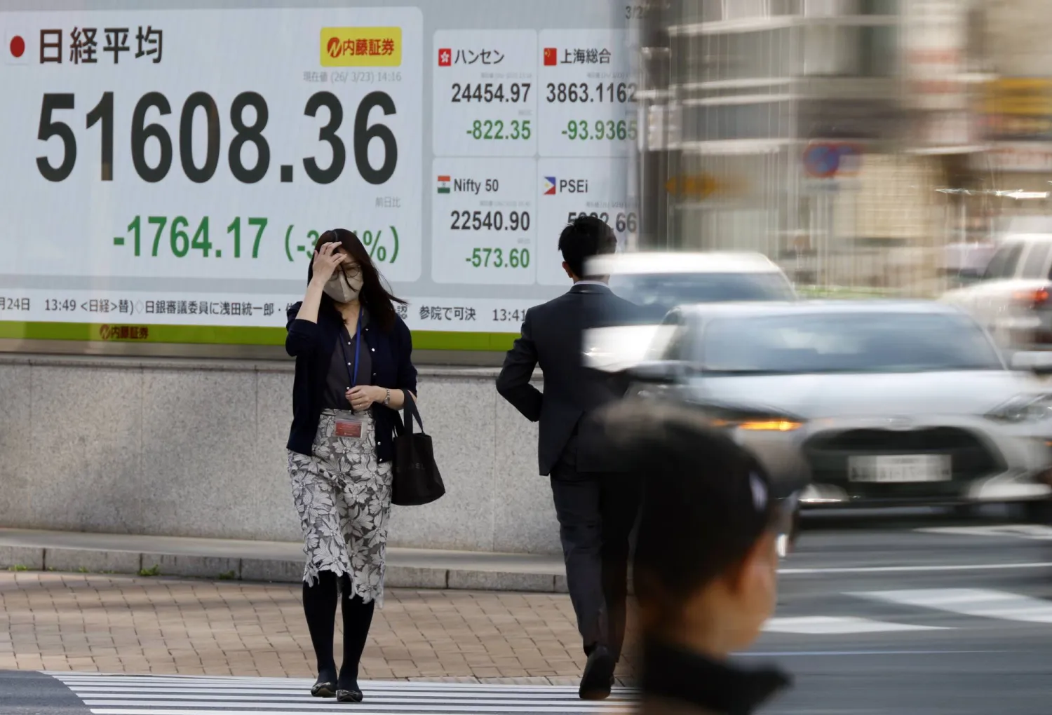 مشاة أمام شاشة تعرض حركة الأسهم في وسط العاصمة اليابانية طوكيو (إ.ب.أ)