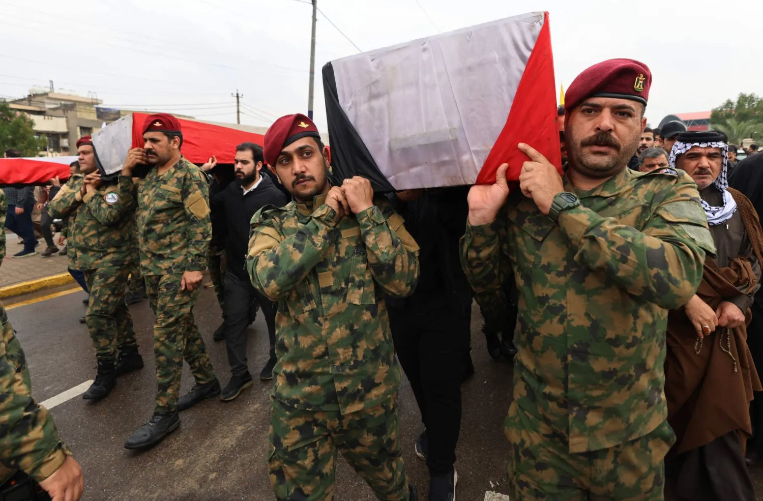 Members of Iraq's PMF carry the coffin of the PMF operations commander for Al-Anbar, Saad Dawai alongside others during a mass funeral in Baghdad on March 24, 2026. (AFP) 