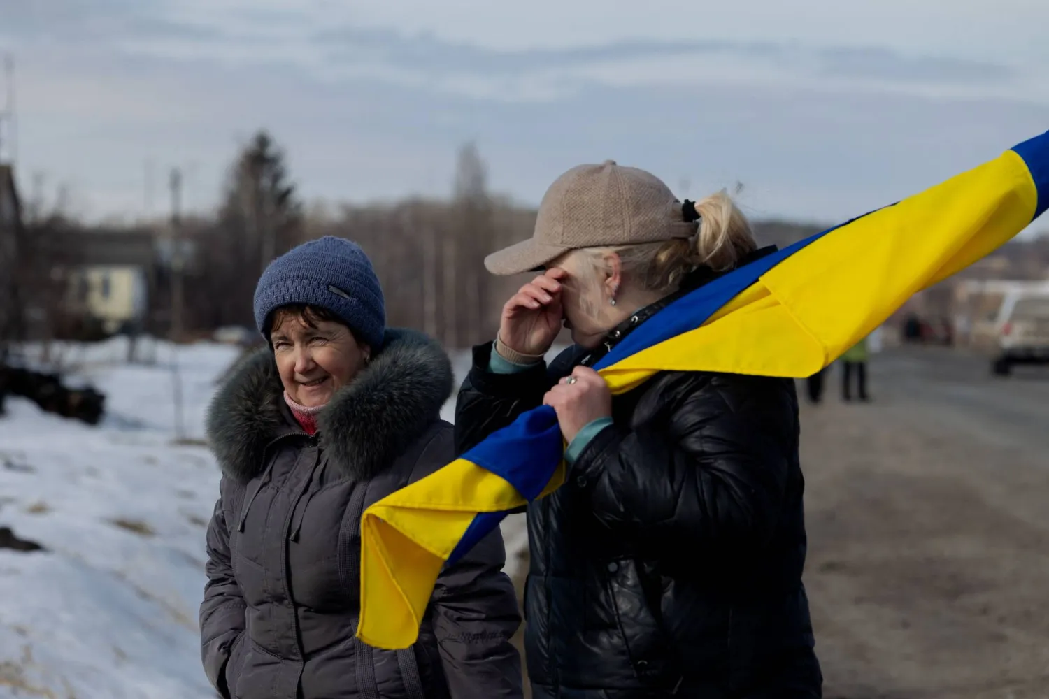 A woman is holding a Ukrainian flag and crying after the buses with released Ukrainian prisoners of war (POW) drove by in the Chernihiv region on March 6, 2026, amid the Russian invasion of Ukraine. (AFP) 