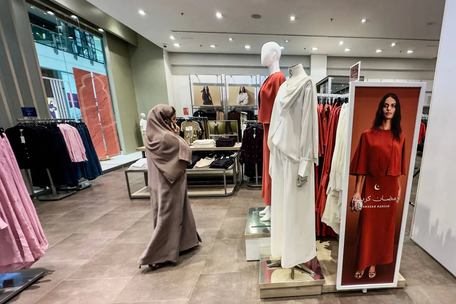 A woman speaks on her mobile phone as she browses a shop for new clothes ahead of the start of the Eid al-Fitr festival in Dubai on March 16, 2026. (Photo by AFP) 